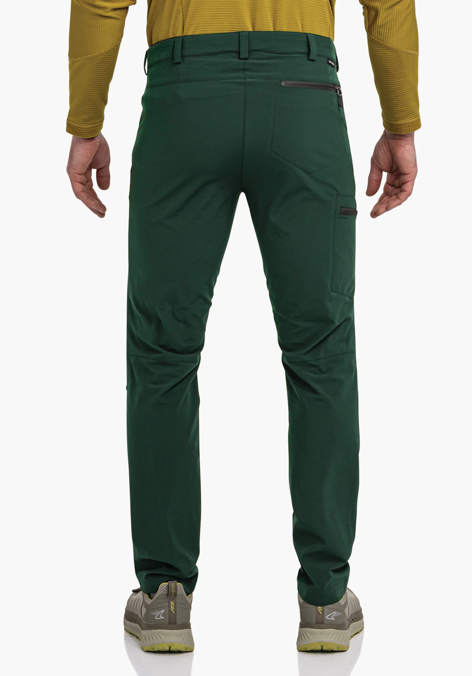 Pants Folkstone donkergroene broek, gedragen door een staande persoon; sluit aan op het lichaam, toont zak- en ritssluitingsdetails; achteraanzicht met donkergeel bovenstuk en sneakers tegen een witte achtergrond.