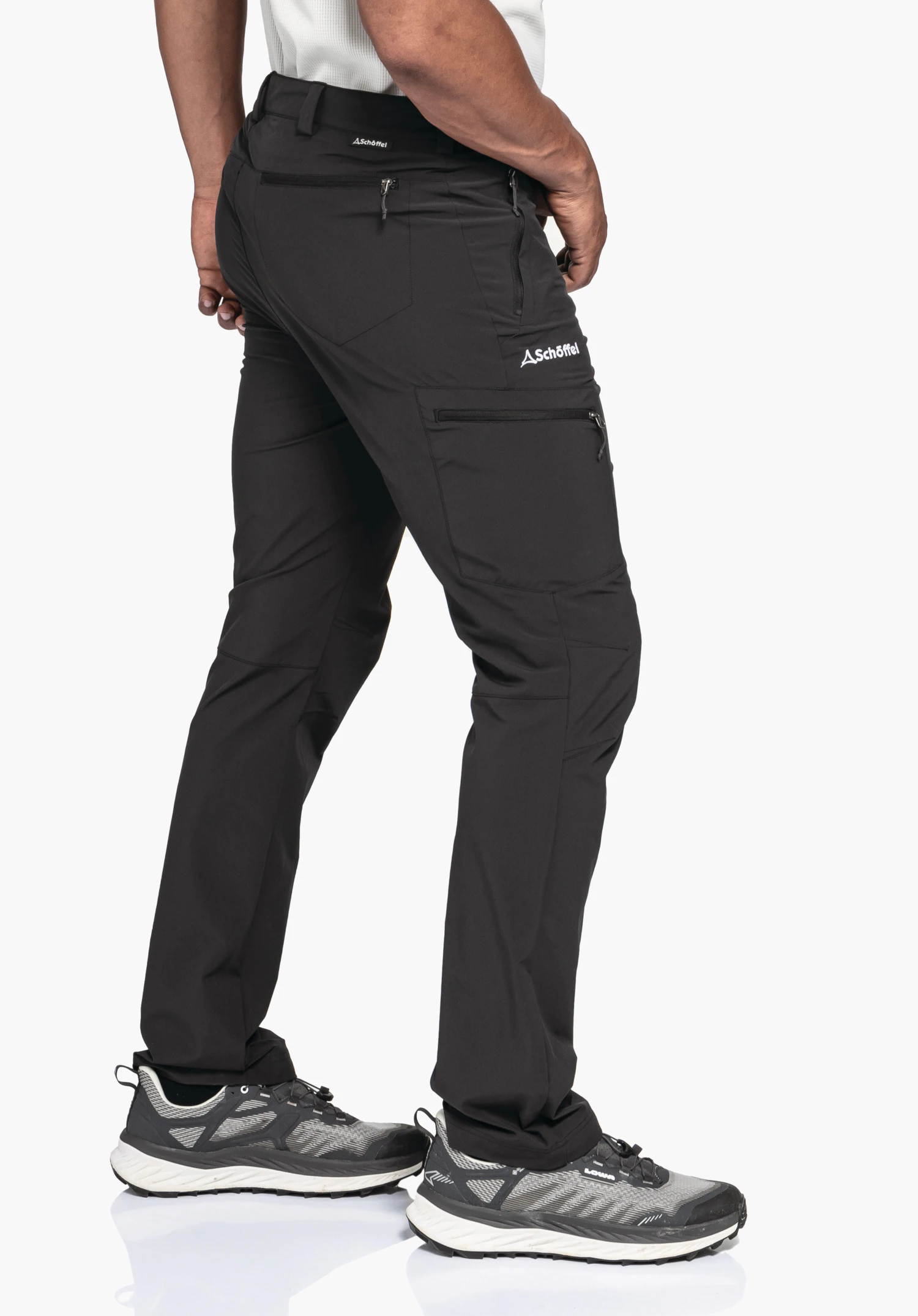 Pants Folkstone in Schwarz präsentiert in einer seitlichen Ansicht vor einem neutralen Hintergrund. Das Model trägt die Hose mit gut sichtbarem Schöffel-Logo auf dem Oberschenkel und am rückwärtigen Bund, was die funktionale Passform für den Winter unterstreicht.