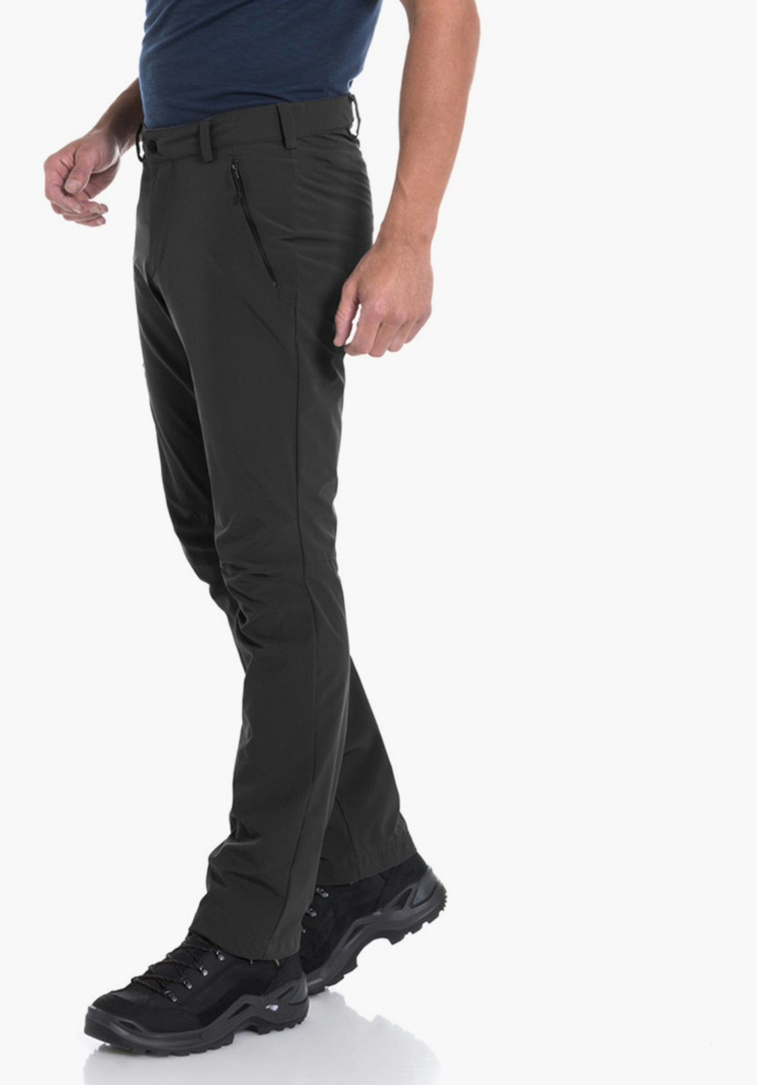 Pants Folkstone man stands side-on taking a step, wears a dark blue T-shirt, dark green trousers and black hiking boots in front of a white studio background.