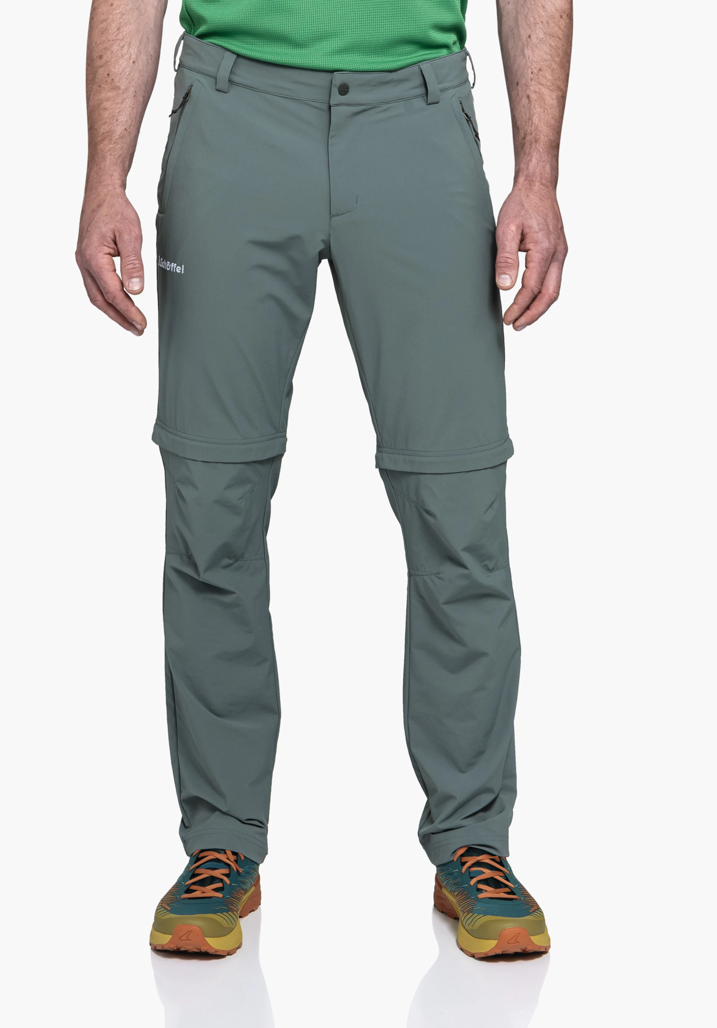 Pants Folkstone Zip Off gedragen door een model dat frontaal staat. Je ziet de grijze broek met afritsbare pijpen en het Schöffel-logo op het rechter bovenbeen voor een neutrale achtergrond.