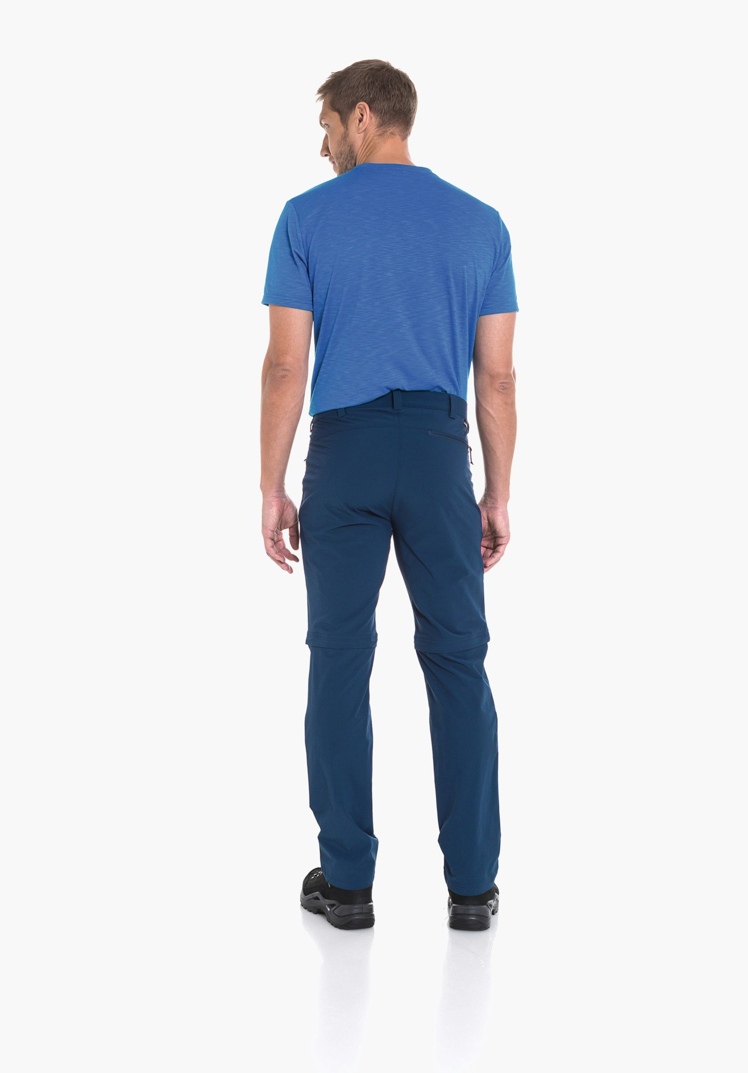 Pants Folkstone Zip Off man seen from the back wearing a light blue T-shirt and dark blue trousers with knee zip; standing against a white background, looking slightly left; black shoes.