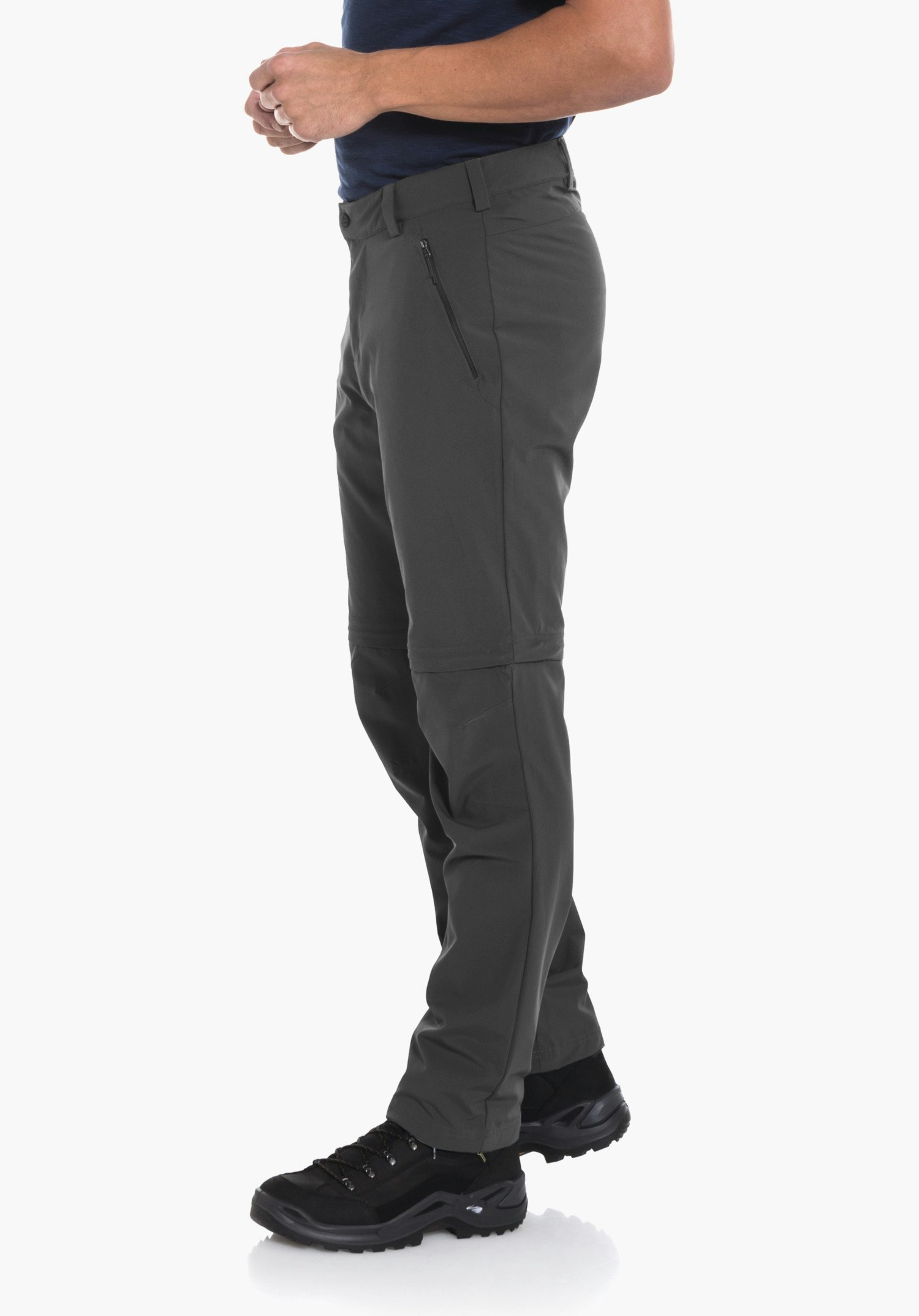 Pants Folkstone Zip Off man stands side-on holding his hands loosely in front of his abdomen, wears a dark blue T-shirt, dark green trousers and black hiking boots; white studio background.
