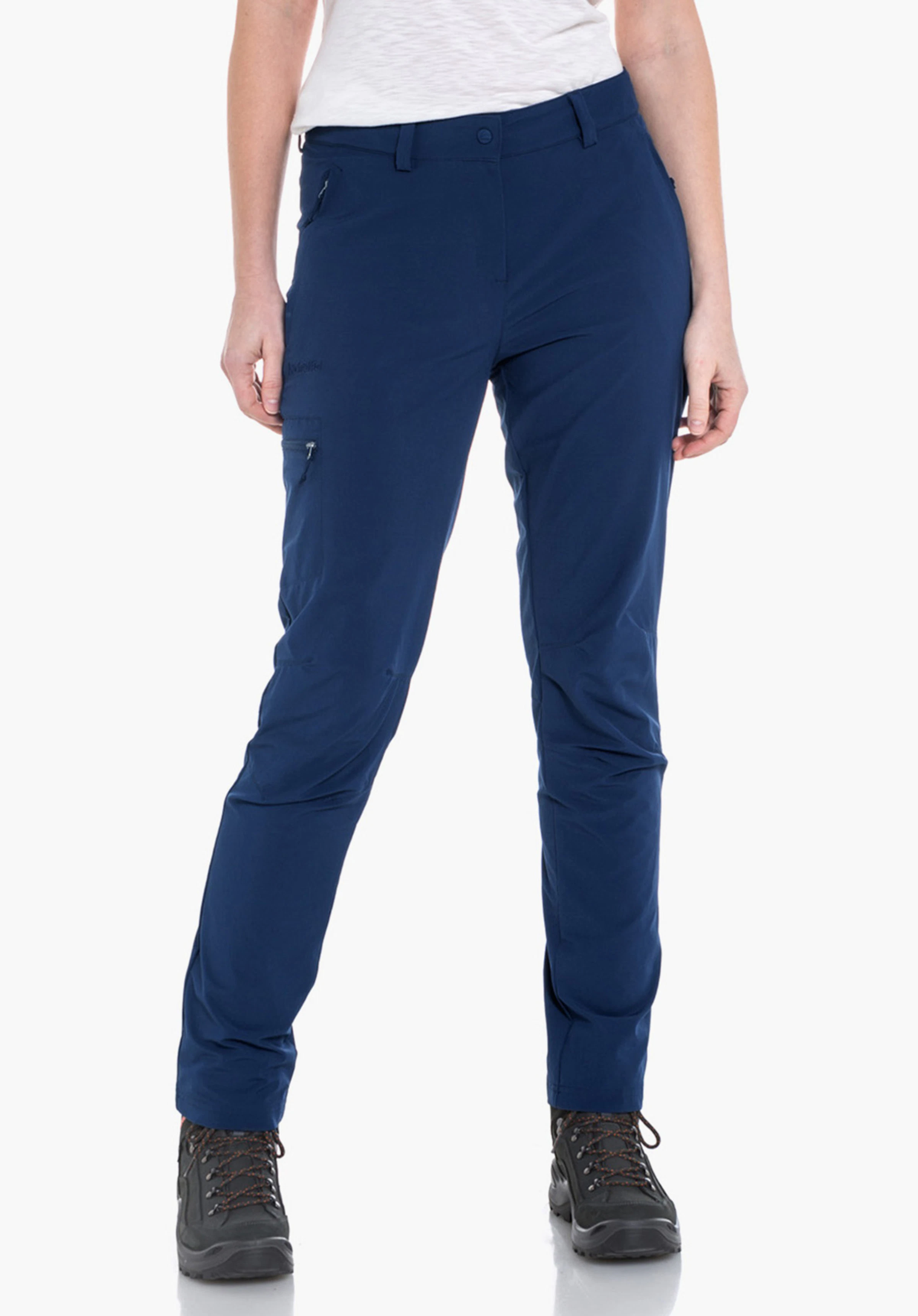 Pants Ascona Pantalon femme: femme portant un pantalon bleu foncé, debout droite, mains détendues le long du corps; t-shirt blanc lumineux et chaussures de randonnée noires sur fond blanc.