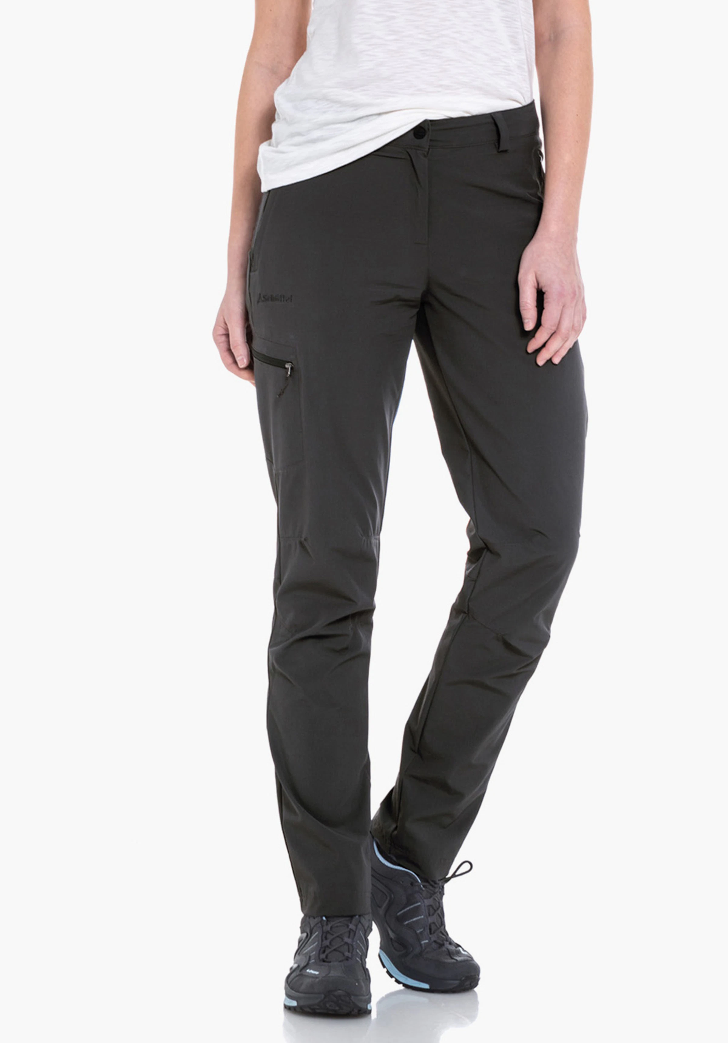 Pants Ascona Pantalon outdoor gris foncé porté par une personne debout; jambes légèrement écartées, combiné avec une chemise à carreaux vert clair et rouge et des chaussures de randonnée gris clair, fond studio blanc.