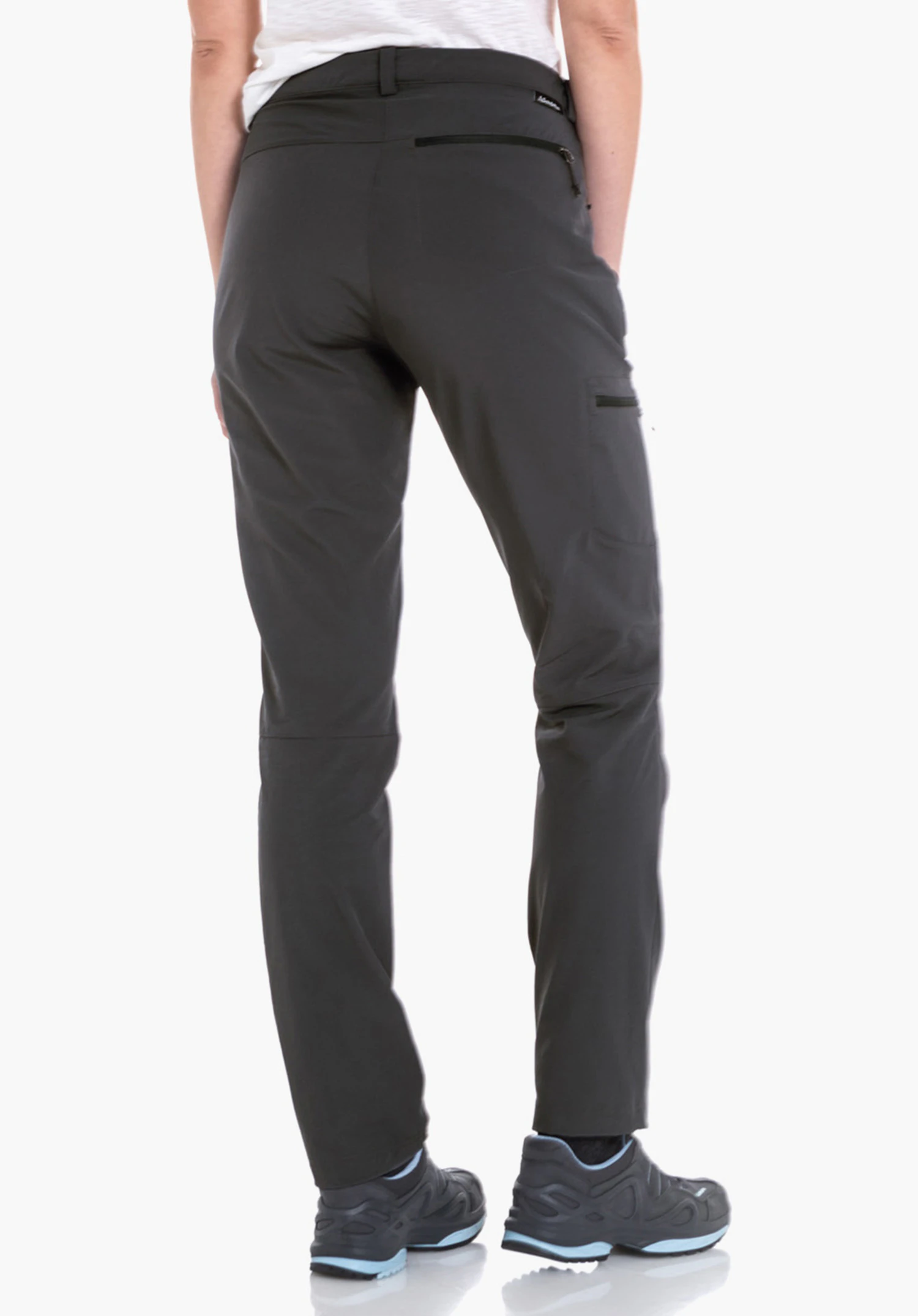 Pants Ascona black outdoor trousers worn from the back; person stands wearing a light green and red checked shirt; back pocket and hiking shoes visible; white background.