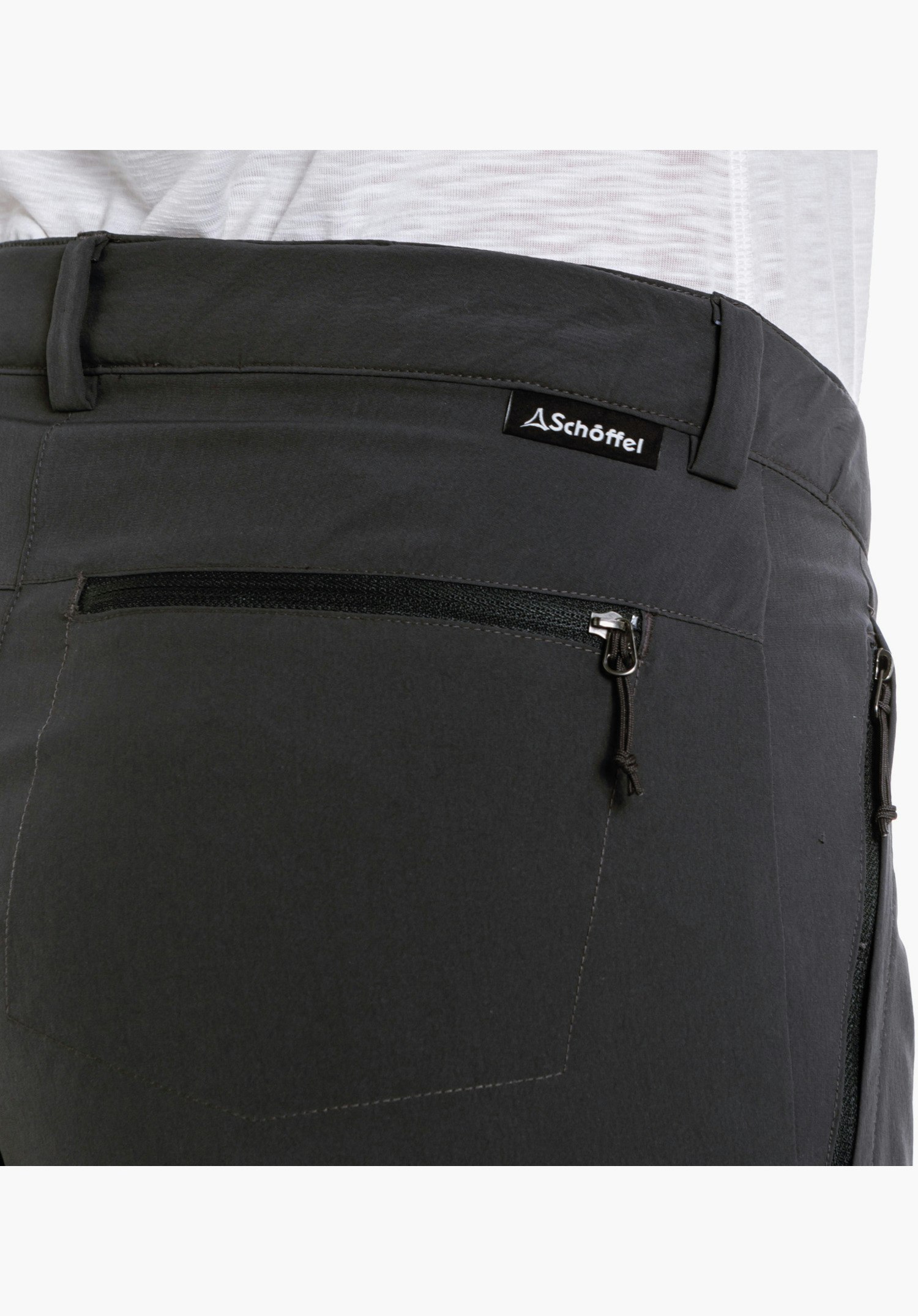 Pants Ascona, Detailansicht der Reißverschlusstasche am Oberschenkel mit Schöffel-Logo und die Struktur des grauen Materials, Nahaufnahme vor weißem/neutralem Hintergrund.