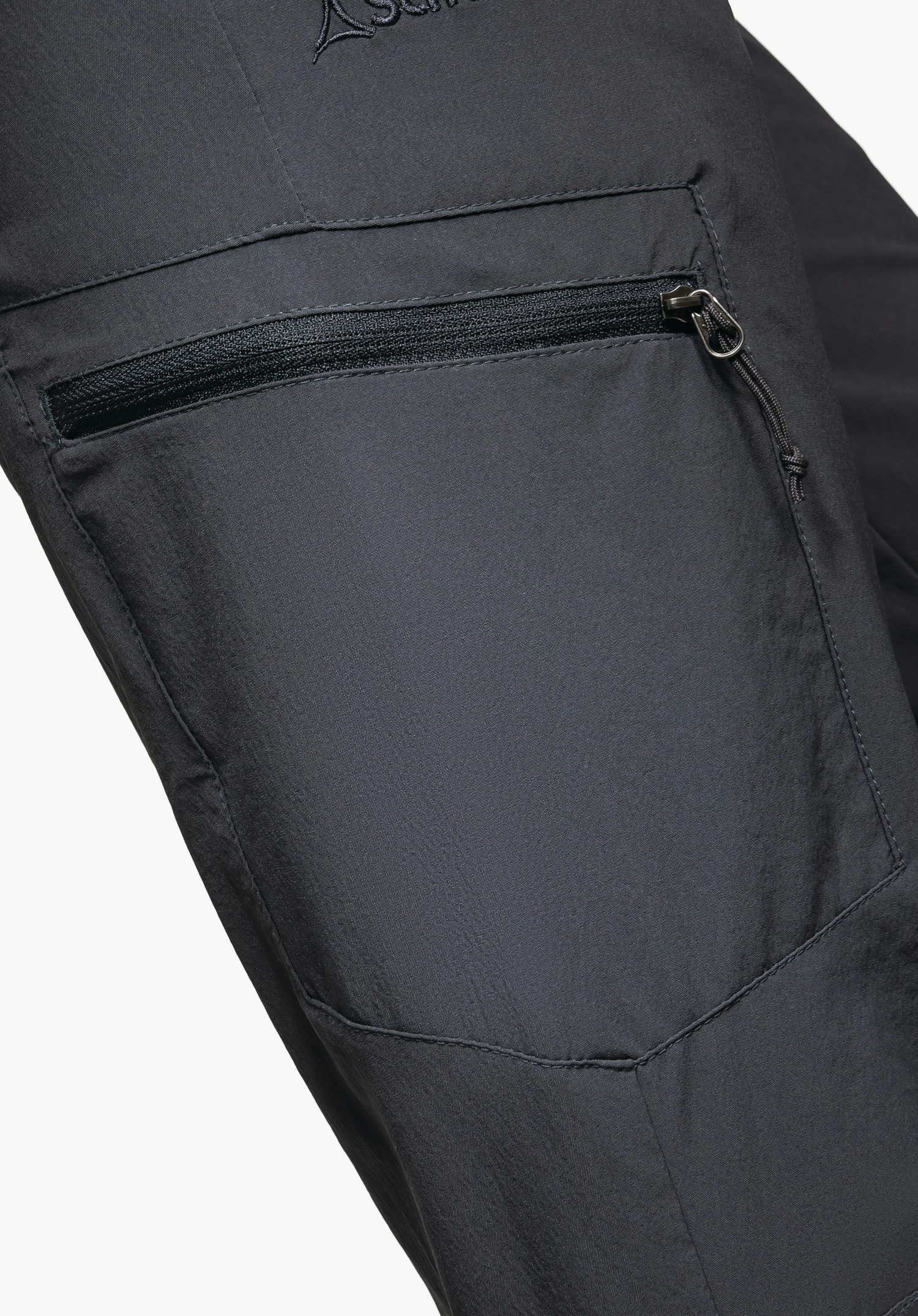 Pants Ascona zeigt die wasserabweisende graue Materialoberfläche mit abperlenden Wassertropfen, einem wasserfesten Reißverschluss und dem Schöffel-Logo als Nahaufnahme vor weißem/neutralem Hintergrund.