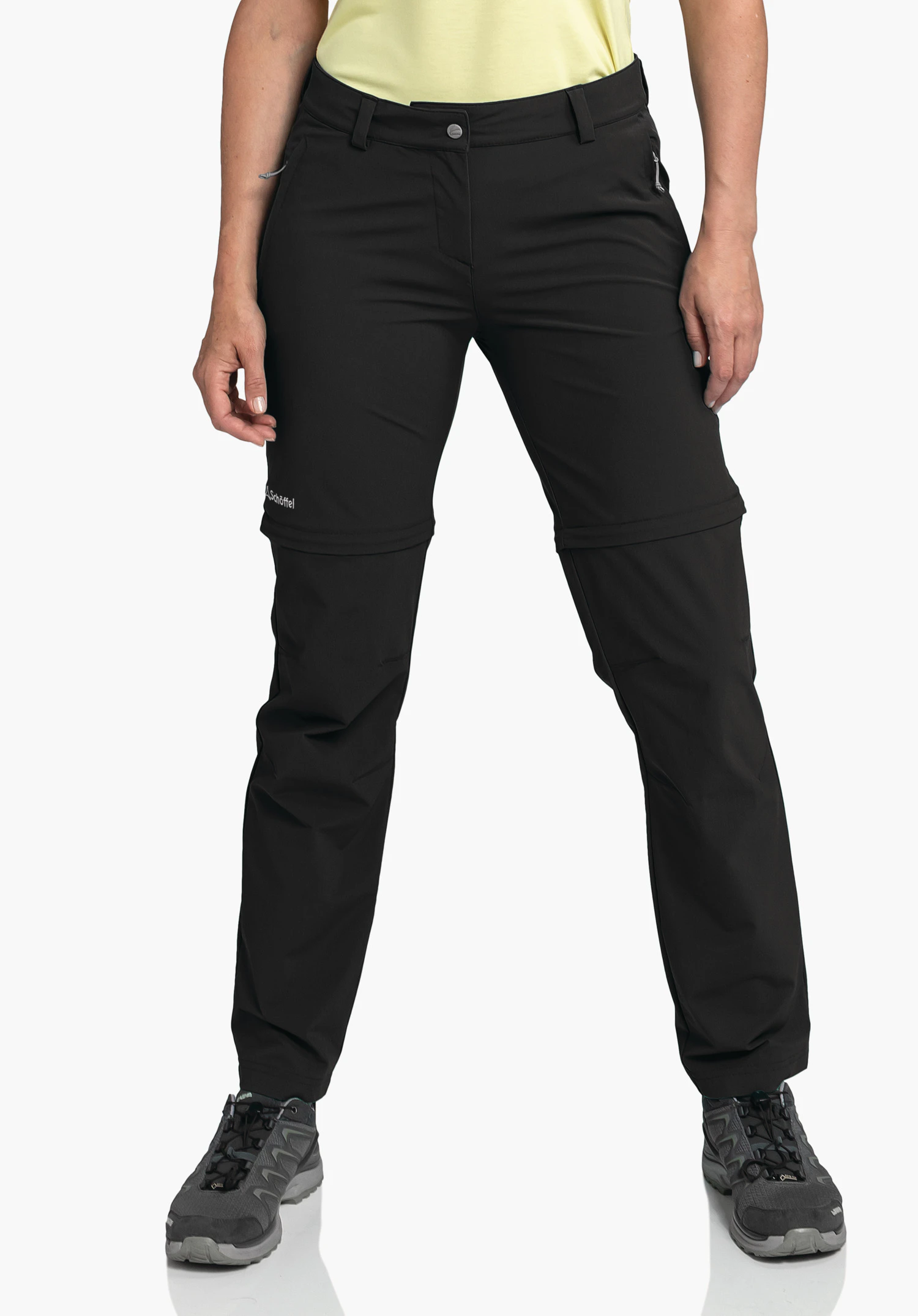 Pants Ascona Zip Off. A model stands frontally wearing the black trousers with a visible Schöffel logo on the right thigh, set against a neutral background.