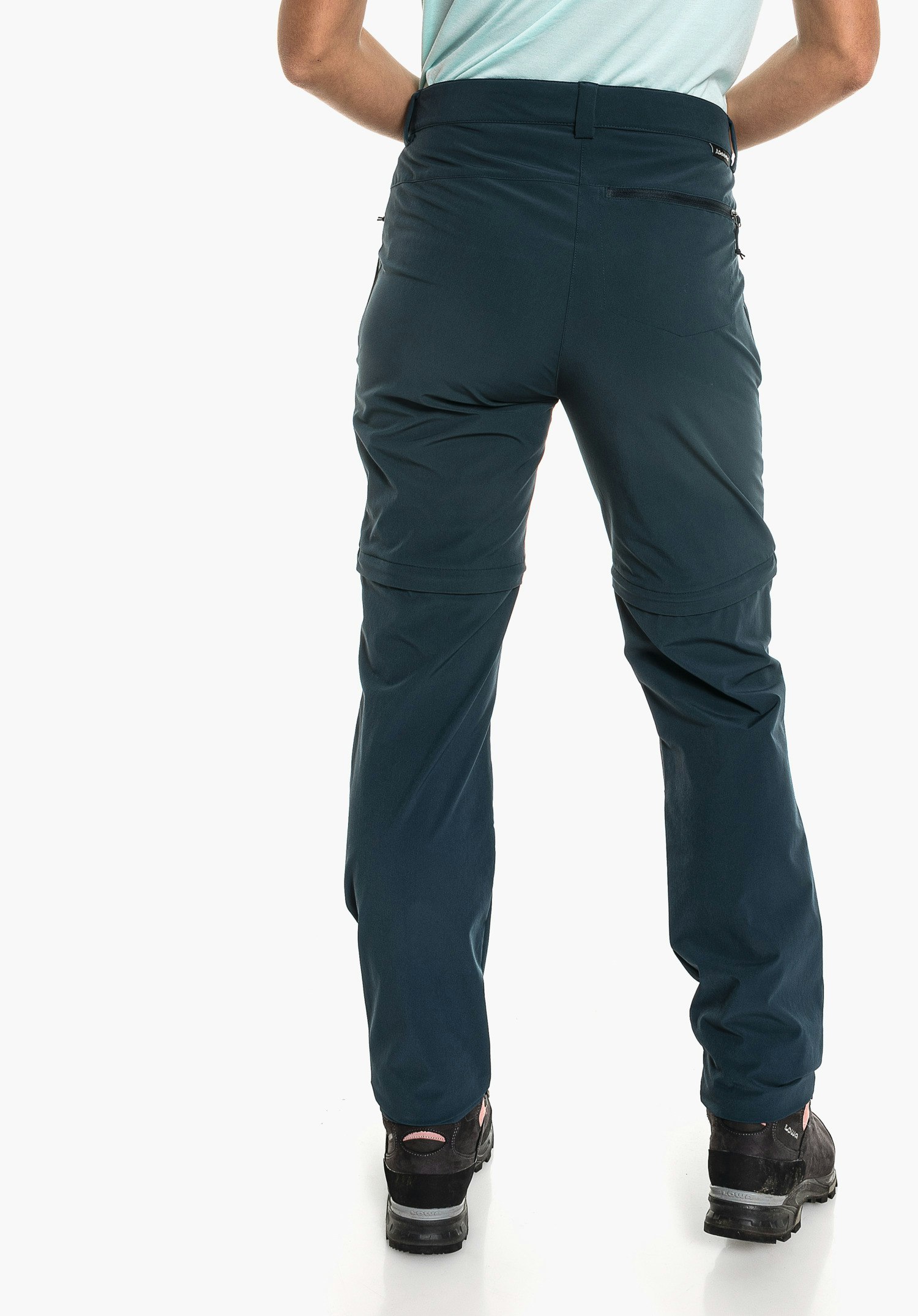 Pants Ascona Zip Off dark blue zip-off hiking trousers; person stands from the back against a white studio background, wearing black hiking shoes. Text: LOWA.