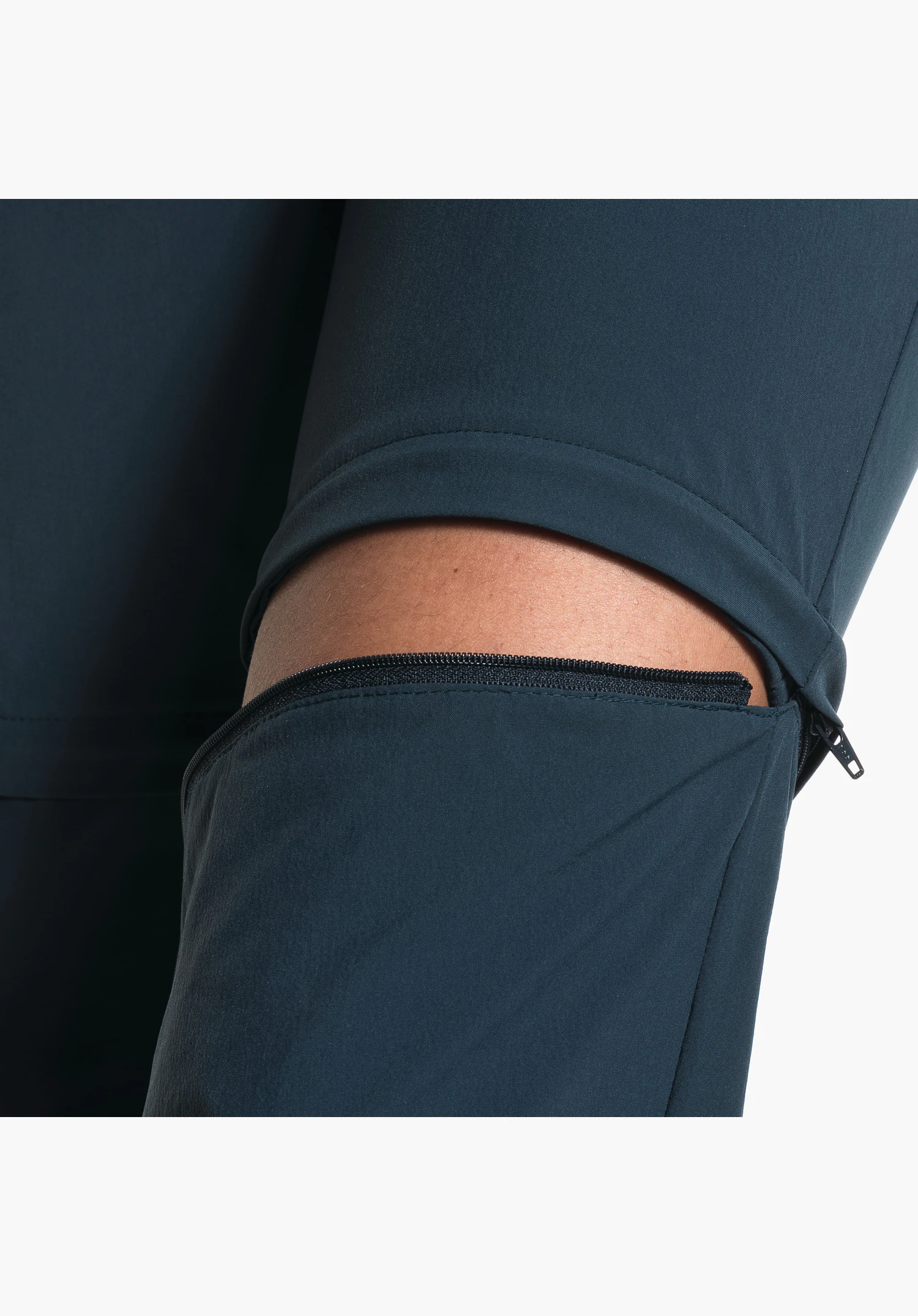 Pants Ascona Zip Off zeigt den Reißverschluss der abzippbaren Hosenbeine und das blaue Funktionsgewebe. Nahaufnahme vor weißem Hintergrund.