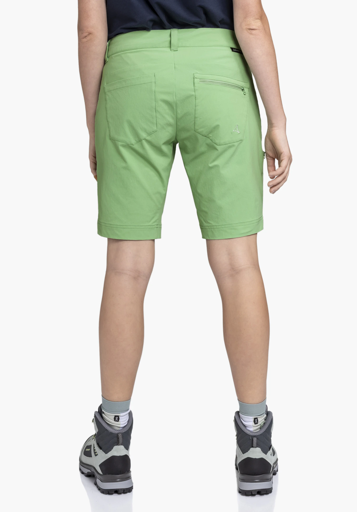 Shorts Toblach2 gedragen door een model in achteraanzicht. De groene korte broek toont twee achterzakken, waarvan één met rits, en het Schöffel-logo aan de rechterkant, en wordt gepresenteerd tegen een neutrale achtergrond.