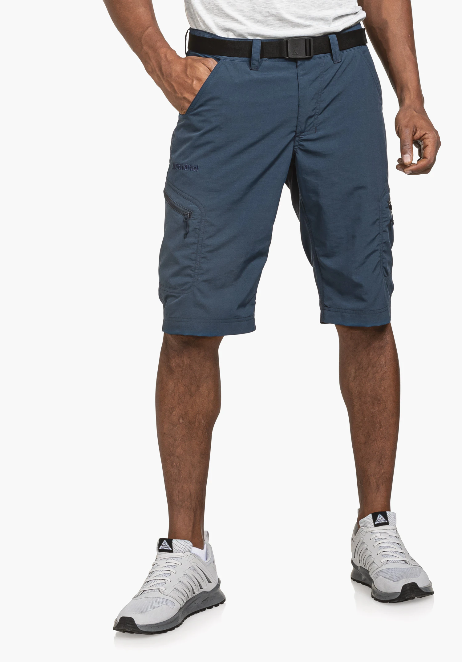 Shorts Silvaplana2 in blue, worn by a model. The model stands facing forwards with legs slightly apart and the right hand in the trouser pocket, making the Schöffel-Logo clearly visible on the right thigh, against a neutral background.