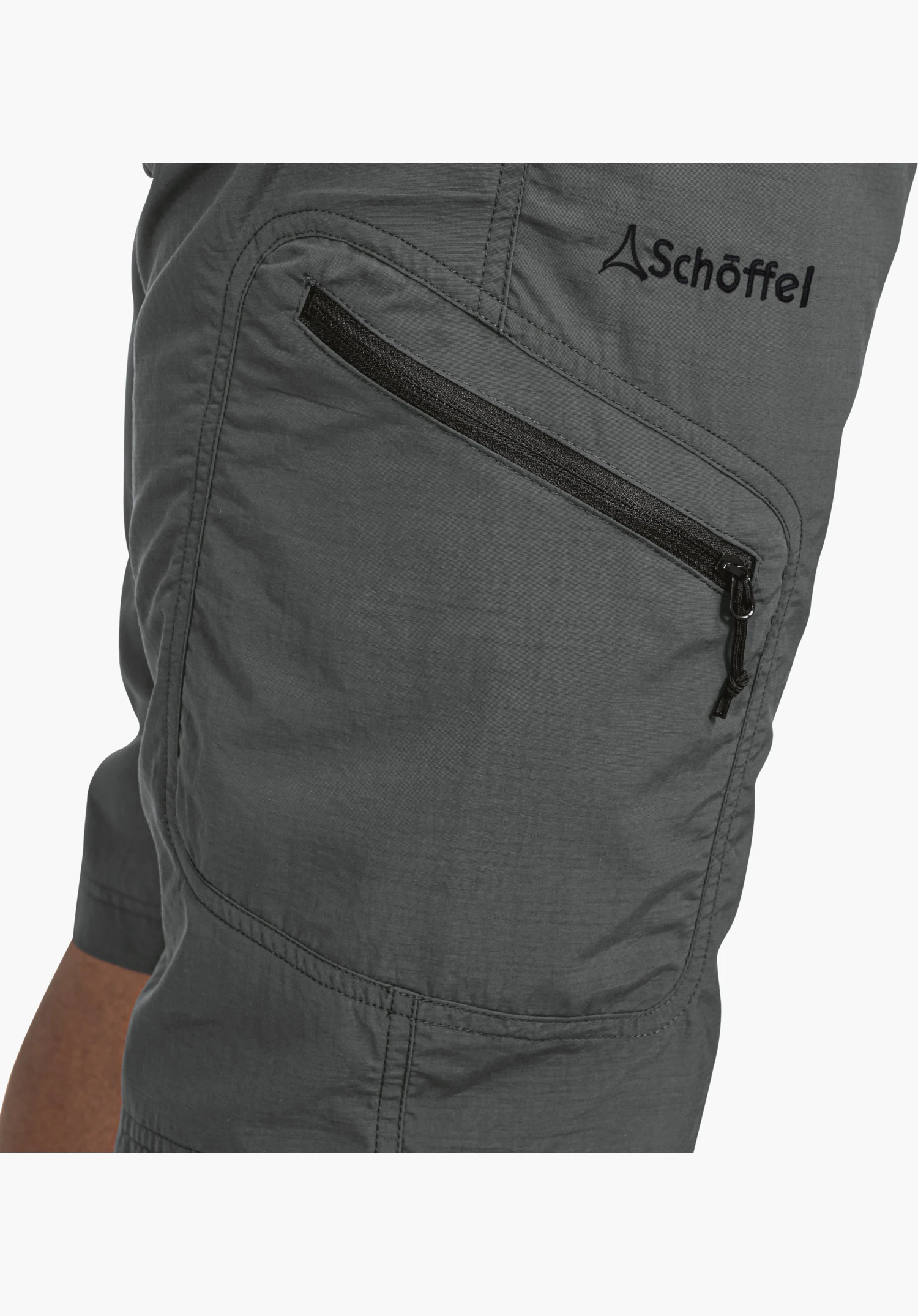 Shorts Silvaplana2 shows a diagonal zip pocket with a black puller and the black Schöffel logo on the grey fabric. Close-up against a white/neutral background.