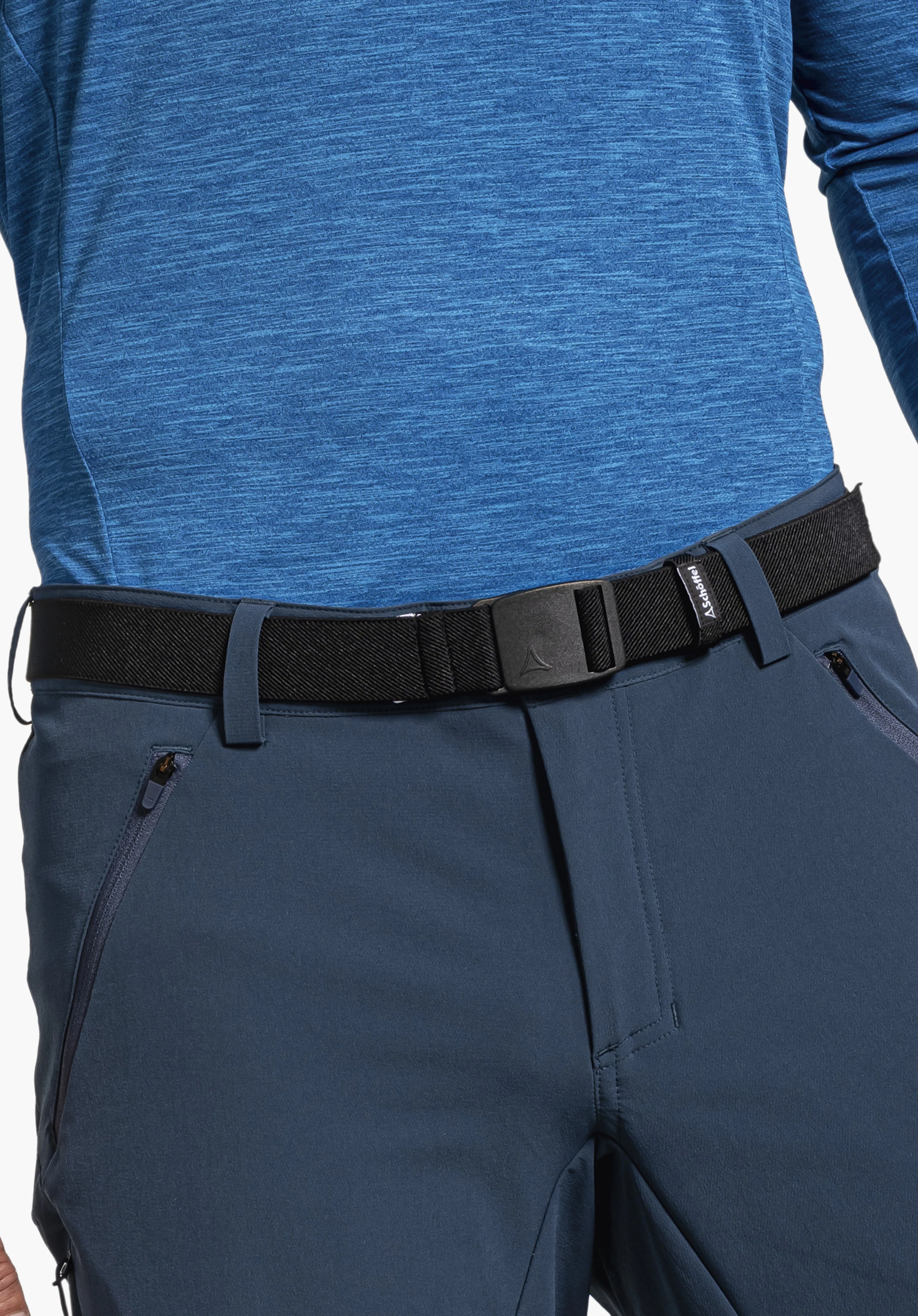Belt Lenzerheide1 Schwarzer Gürtel mit Schöffel-Logo spannt sich um die Taille, sitzt über dunkelblauer Hose und hellblauem Langarmshirt. Text: "Schöffel".