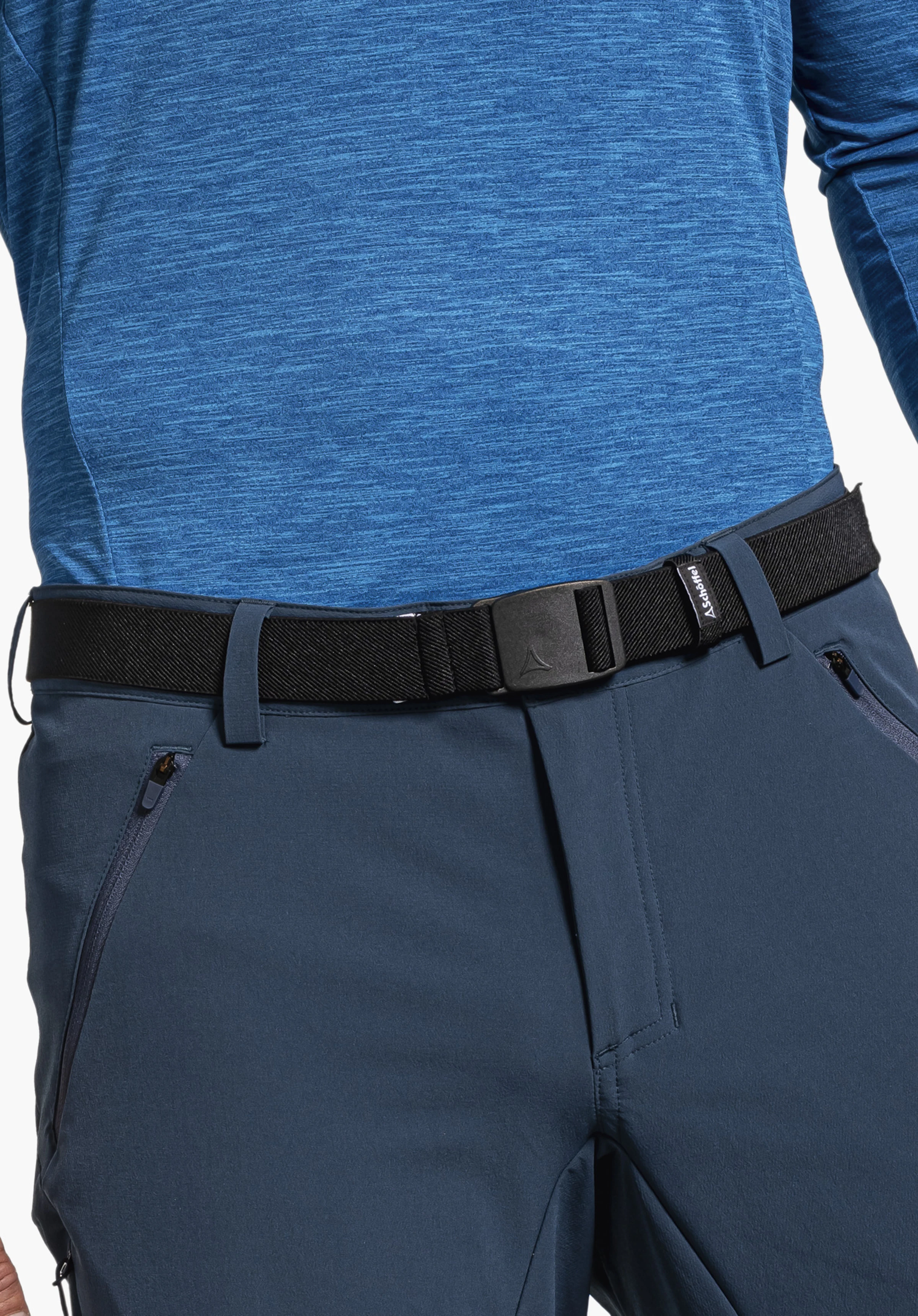 Belt Lenzerheide1 Black belt with Schöffel logo fastened around the waist, worn over dark blue trousers and a light blue long-sleeve shirt. Text: “Schöffel”.