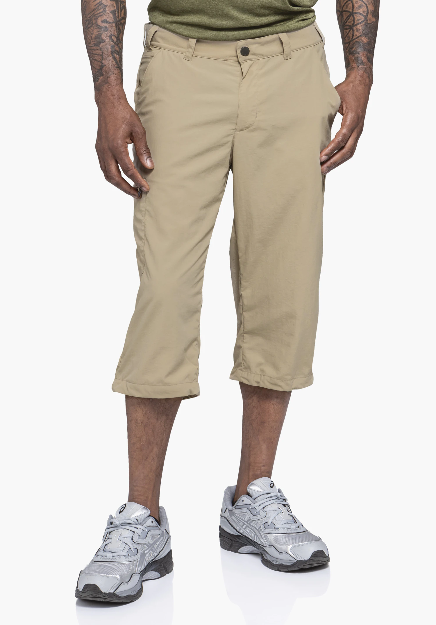 Pants Springdale1 porté par un mannequin se tenant de face. On voit le pantalon 3/4 de couleur beige avec les mains reposant de manière détendue sur les côtés devant un fond neutre.