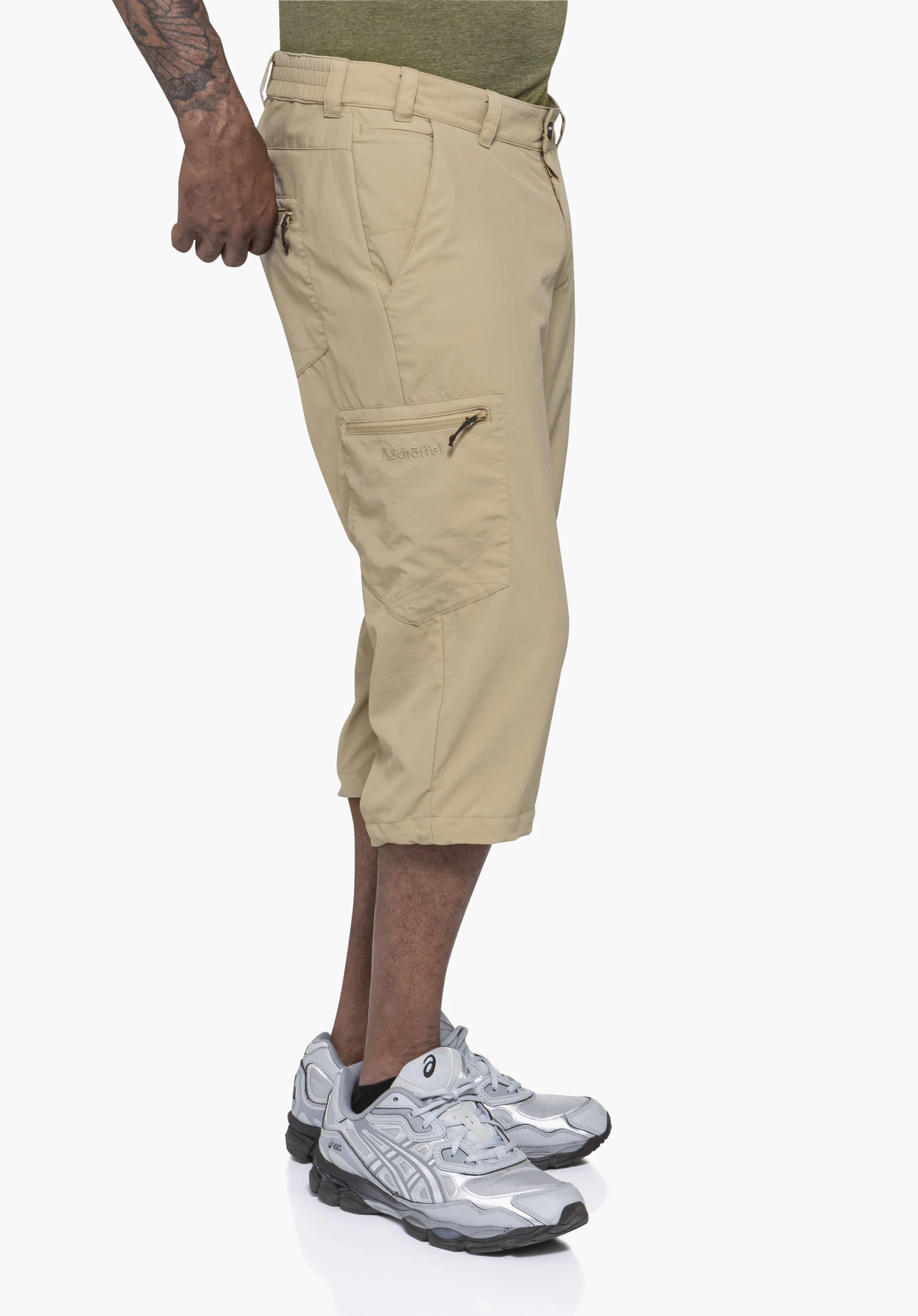 Pants Springdale1 en beige : Un mannequin pose de profil sur un fond neutre pour mettre en valeur la coupe du pantalon. Le logo Schöffel discret est visible sur la poche latérale.