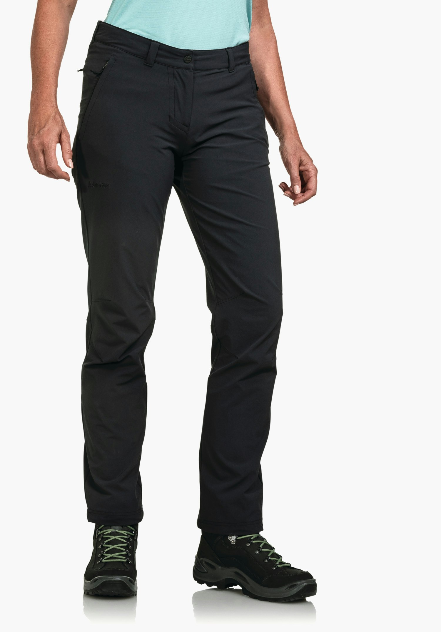 Pants Engadin1 black trekking trousers, worn by a standing person; legs slightly apart, light blue top visible, black hiking shoes with green laces against a white background. Text: “Schöffel”.