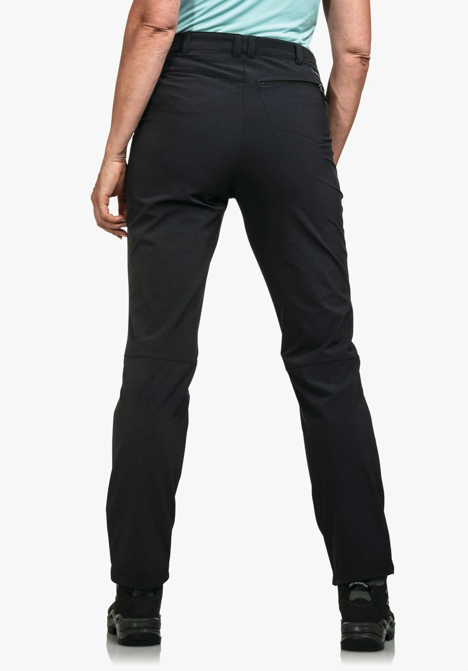Pants Engadin1 deep black outdoor trousers; person stands with back to the camera, legs slightly apart, right hand relaxed at the side; light blue T-shirt, black hiking shoes; white background.