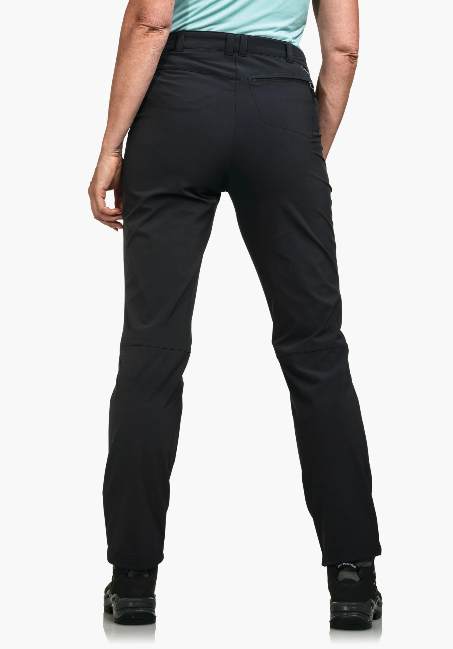 Pants Engadin1 deep black outdoor trousers; person stands with back to the camera, legs slightly apart, right hand relaxed at the side; light blue T-shirt, black hiking shoes; white background.