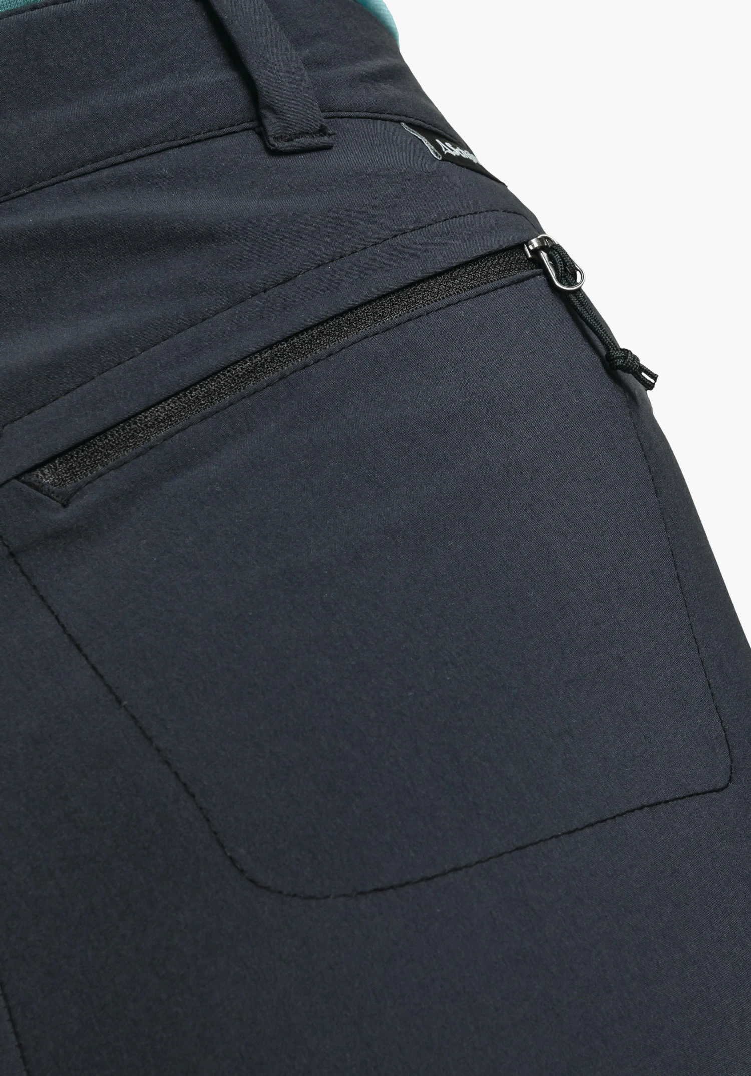 Pants Engadin1 showing a zipped pocket on the black fabric and a small Schöffel logo on the waistband, close-up against a white/neutral background.