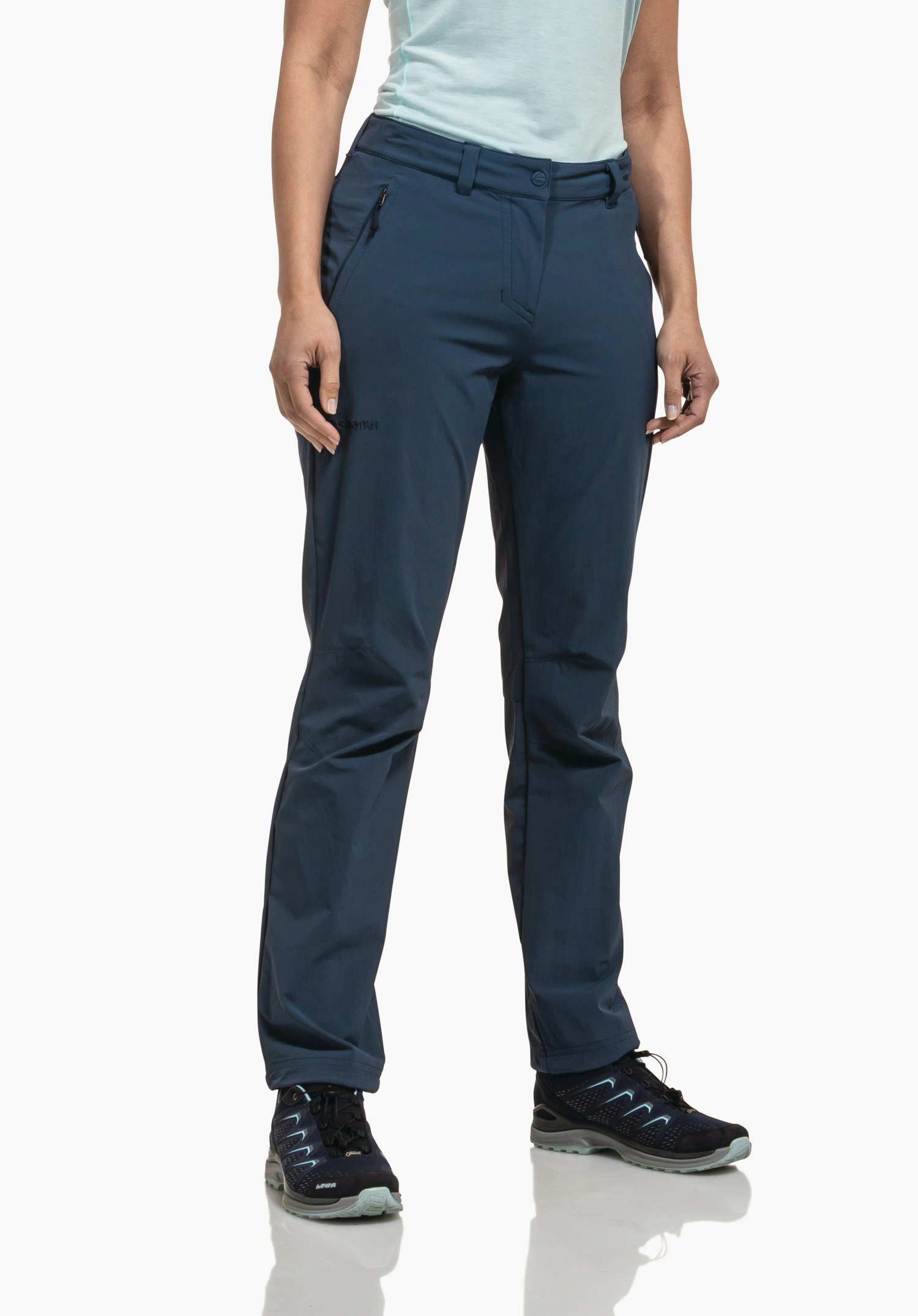 Pants Engadin1 dark blue trousers, worn by a woman standing with hands at her sides; light blue T-shirt, dark sports shoes; white studio background.