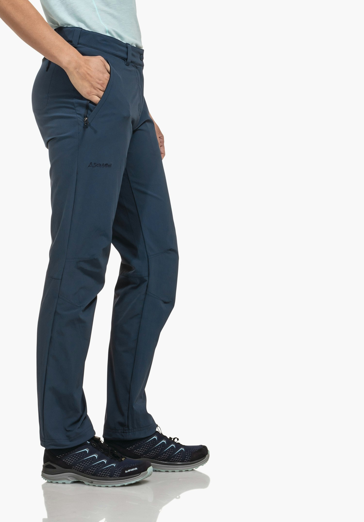 Pants Engadin1 dark blue hiking trousers with one hand in the side pocket; Schöffel triangle logo and lettering "Schöffel" visible; person stands on a white background wearing dark blue hiking shoes with light blue accents.