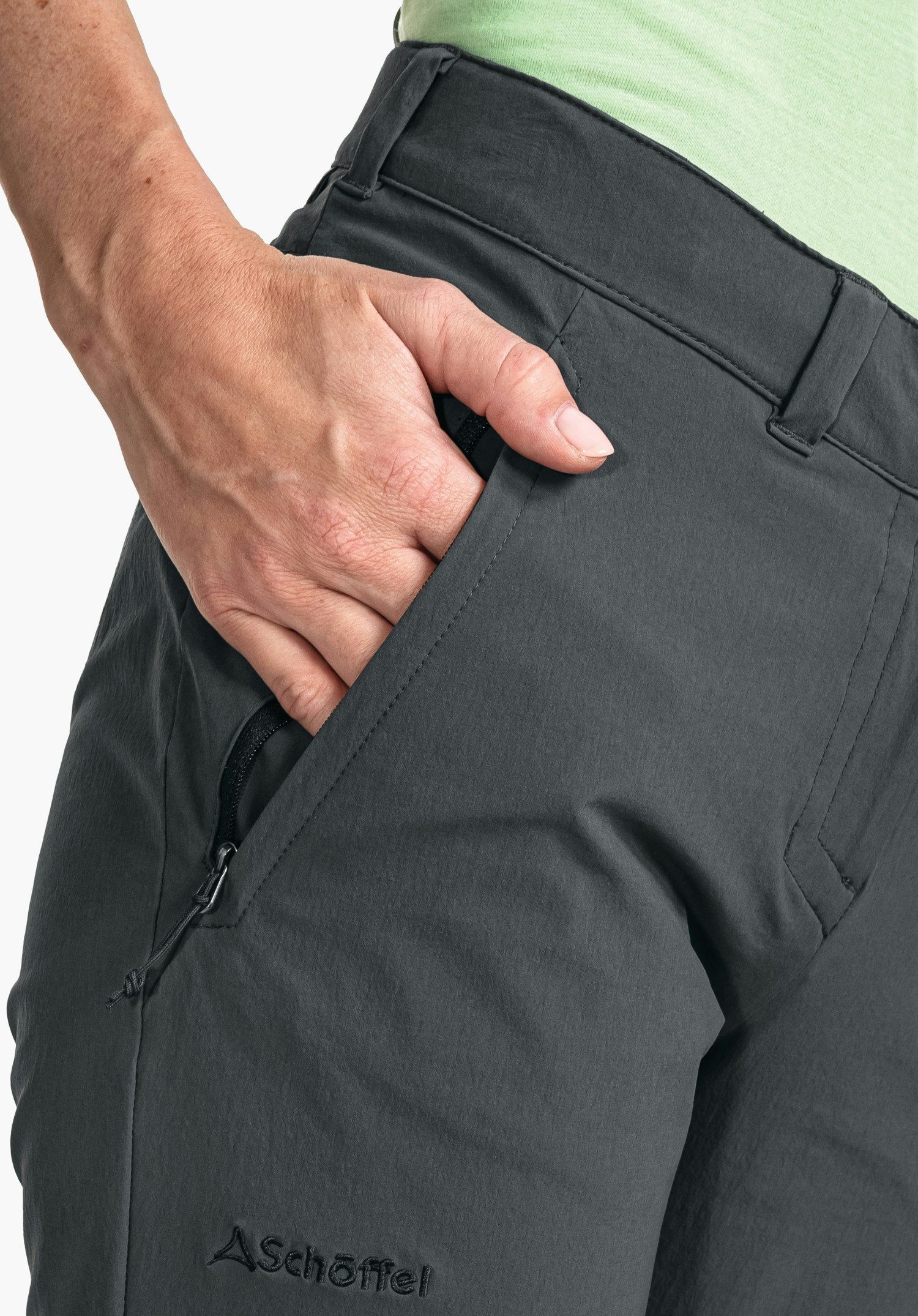 Pants Engadin1 zeigt die seitliche Reißverschlusstasche und das Schöffel-Logo auf dem grauen Stoff in einer Nahaufnahme vor weißem/neutralem Hintergrund.