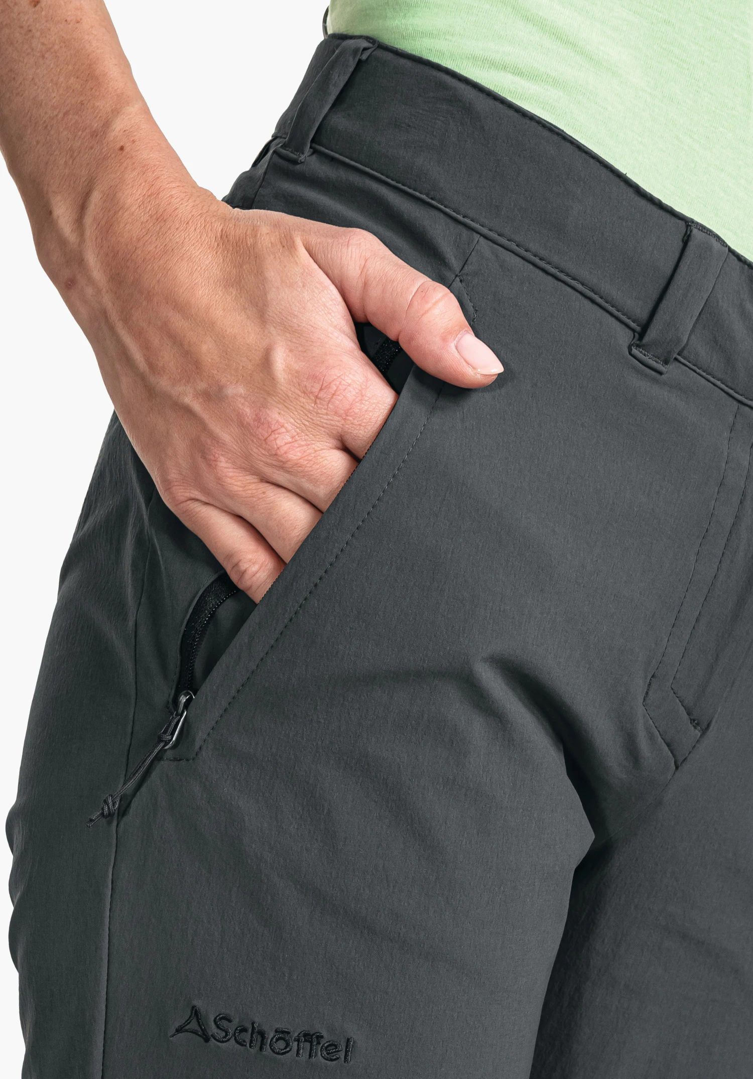 Pants Engadin1 zeigt die seitliche Reißverschlusstasche und das Schöffel-Logo auf dem grauen Stoff in einer Nahaufnahme vor weißem/neutralem Hintergrund.
