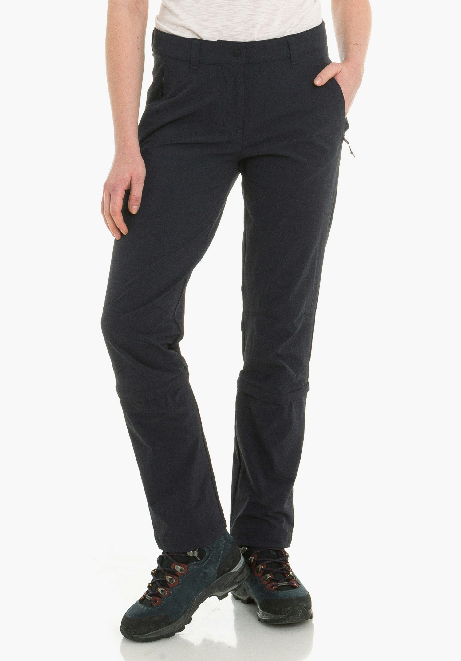 Pants Engadin1 Zip Off dark blue trousers worn standing with right hand in pocket; context: white background, dark blue hiking shoes with red accents, visible waistband.