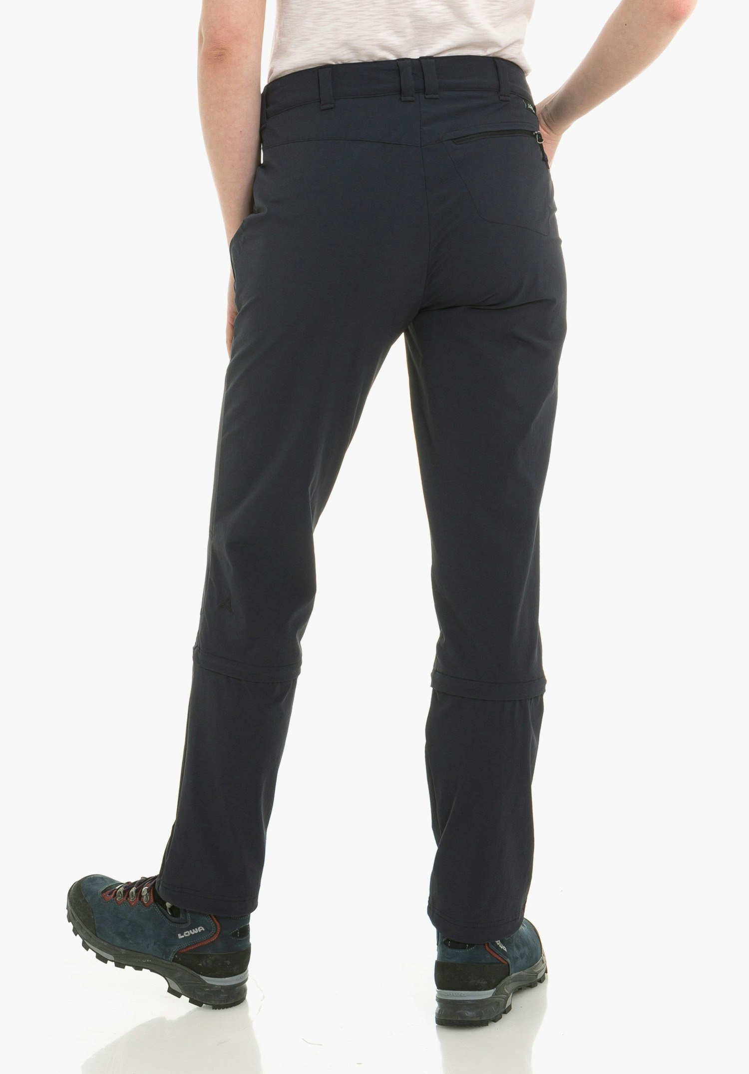 Pants Engadin1 Zip Off dark blue hiking trousers worn from the back by a standing person with legs slightly apart; detachable leg sections with zip, Schöffel logo on the left calf; white background; “LOWA” text on shoe.