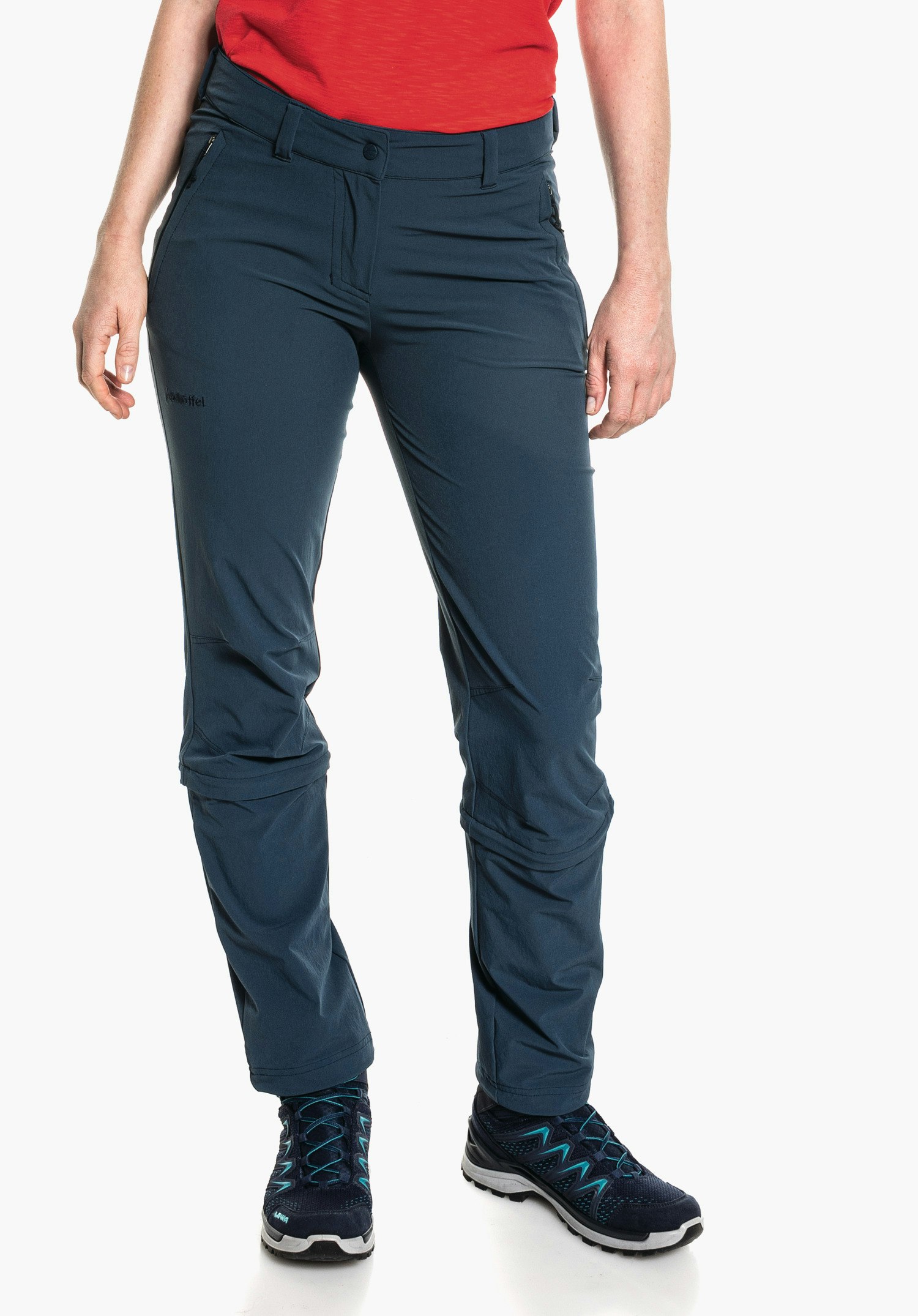 Pants Engadin1 Zip Off dark blue hiking trousers worn by a standing person; legs slightly apart, red shirt, dark blue trekking shoes with light blue accents, white studio background. Text: “Schöffel”, “LOWA”.