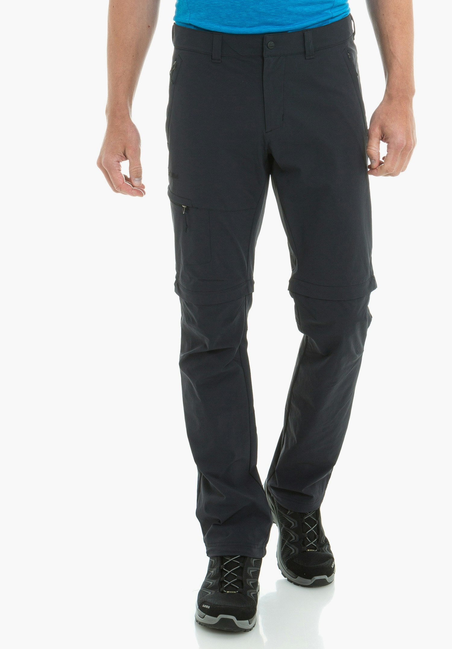 Pants Koper1 Zip Off schwarze Zip-off-Hose, getragen von einer Person, die geht; Kniepartie abnehmbar, kombiniert mit blauem Shirt und schwarzen Wanderschuhen vor neutralem weißen Hintergrund.