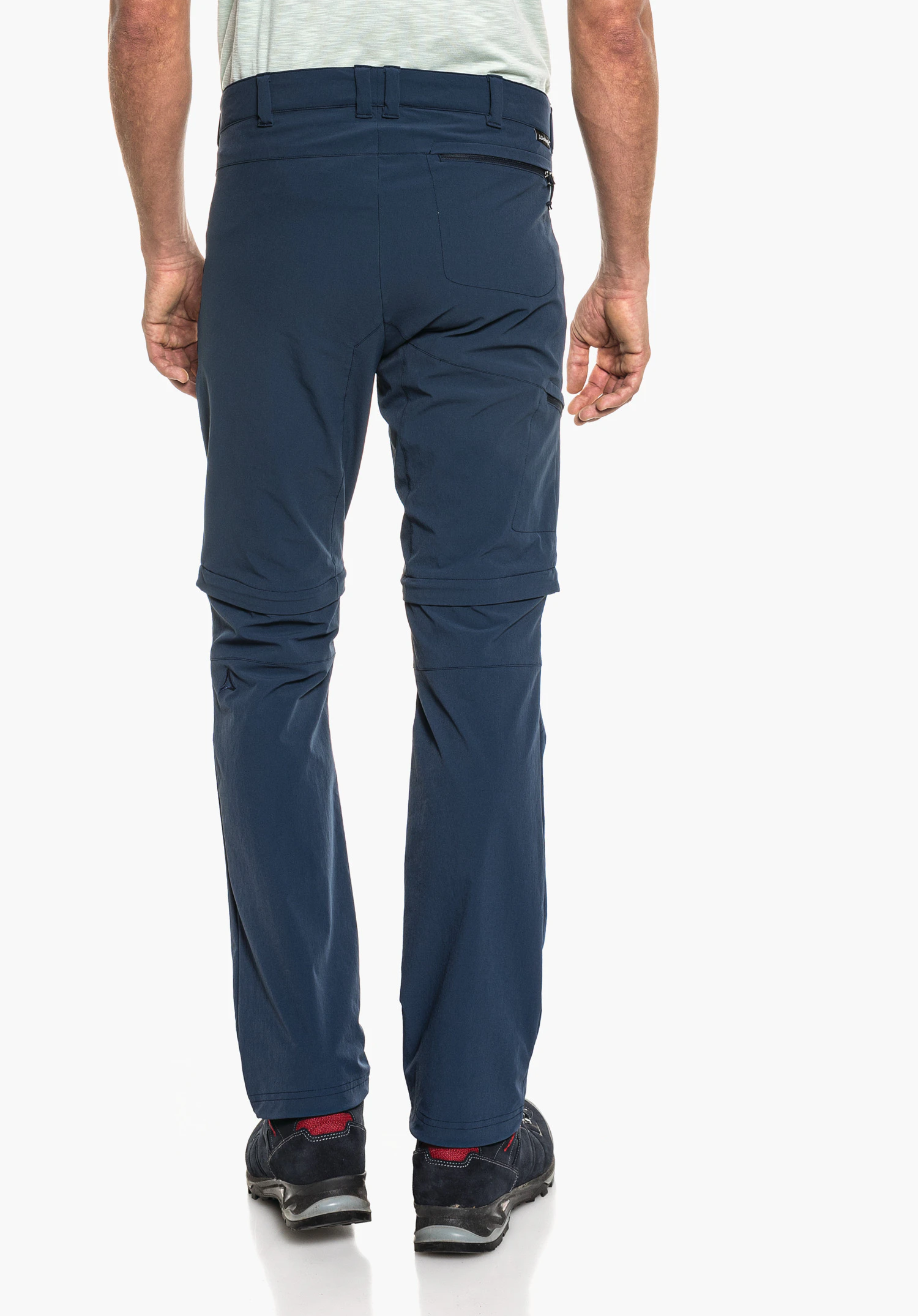 Pants Koper1 Zip Off dark blue zip-off trousers worn by a standing person with their back to the camera; detachable legs at the knees, light grey T-shirt, dark blue shoes; white background.