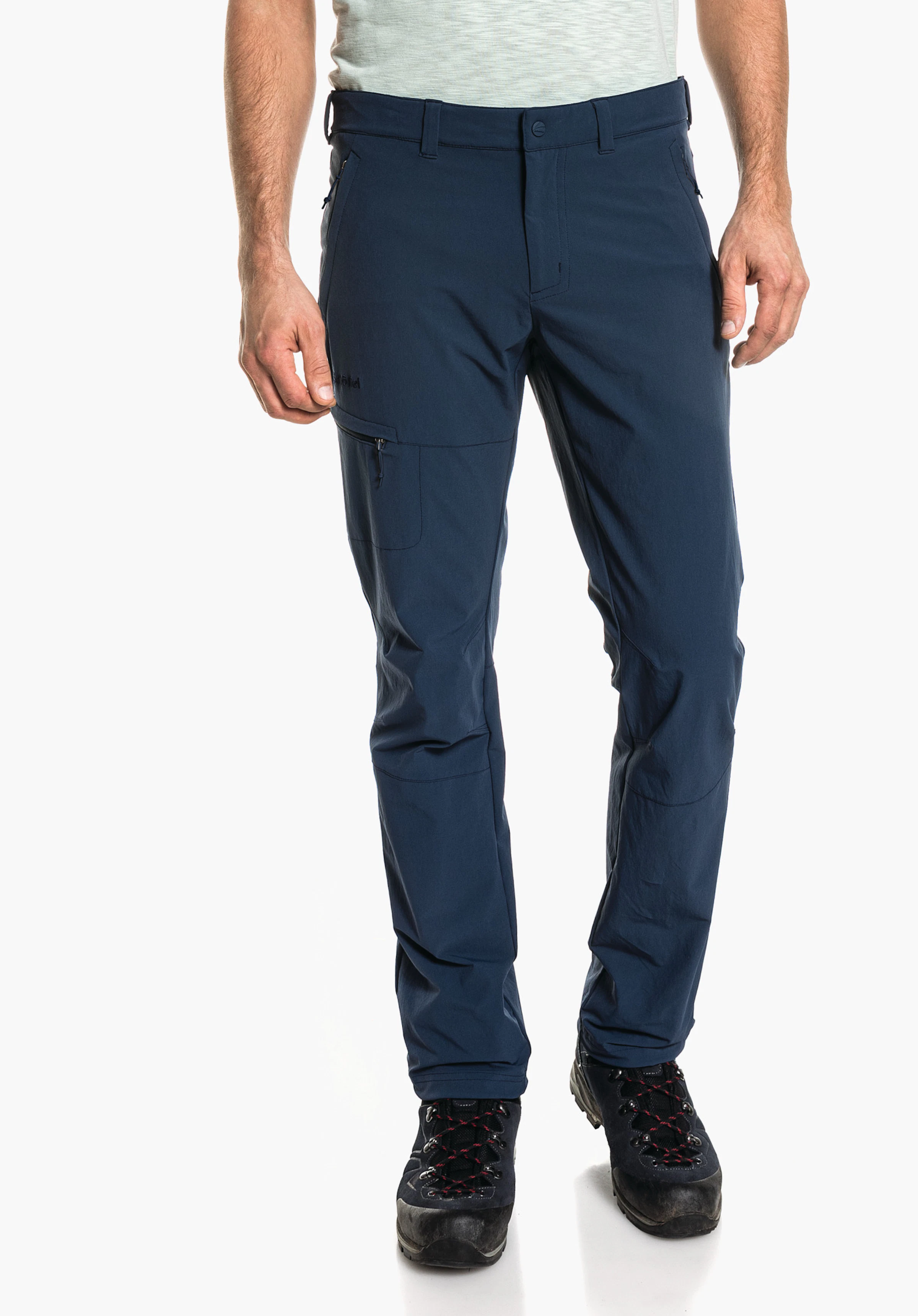 Pants Koper1 dunkelblaue Outdoorhose, sitzt an einem stehenden männlichen Modell; gerade geschnitten, Reißverschlusstasche am Oberschenkel; neutraler weißer Hintergrund. Text: "Schöffel".