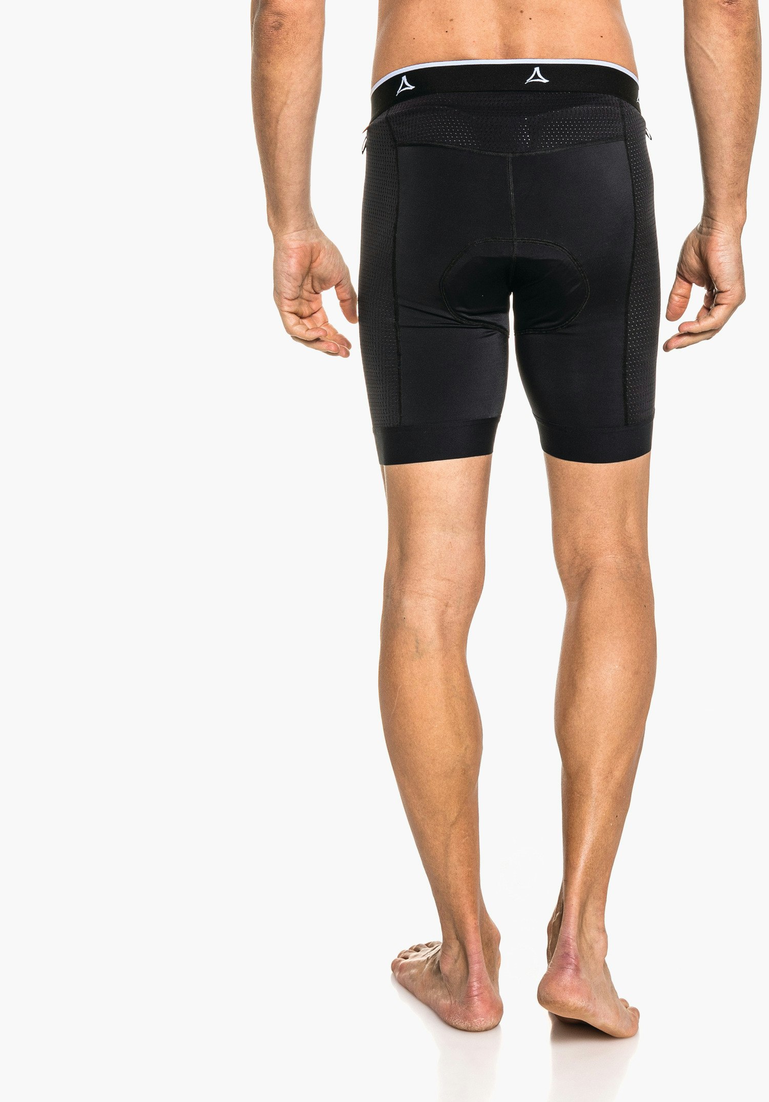 Skin Pants 8h M black padded cycling shorts with Schöffel logo on the waistband; worn by a man, rear view showing padded seat; light skin tone, barefoot; white background.