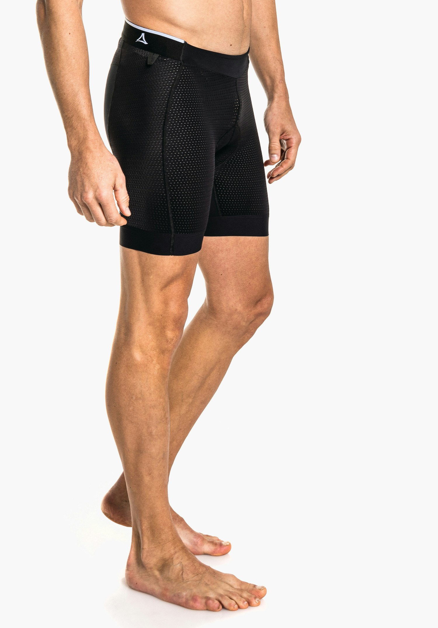 Skin Pants 8h M black perforated boxer shorts with white trim and Schöffel logo, worn by a standing man; barefoot on a light background, upper body and legs visible.