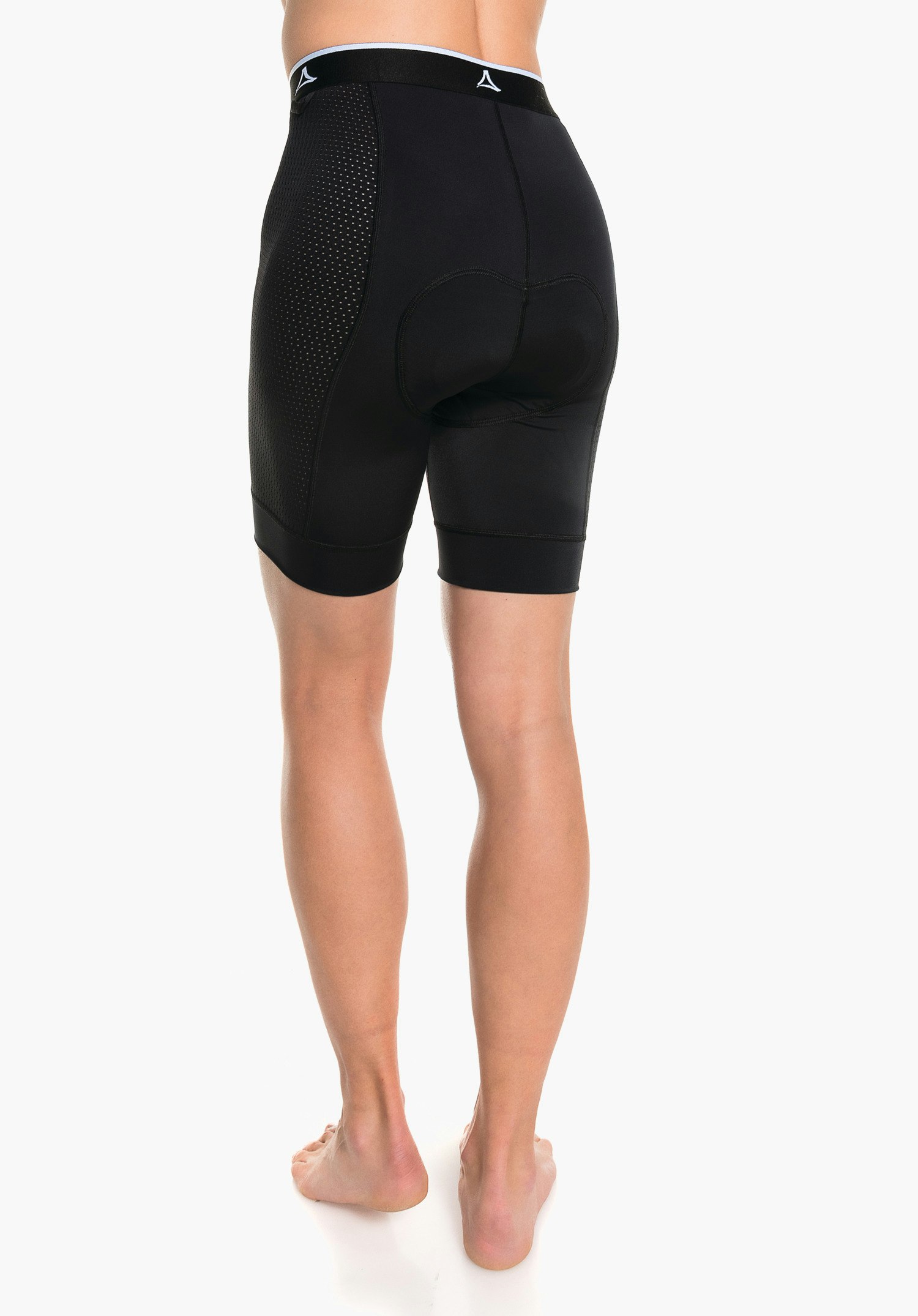 Skin Pants 4h L cuissard cycliste noir rembourré, porté; logo Schöffel sur la ceinture noire. Personne debout pieds nus vue arrière devant un fond blanc.