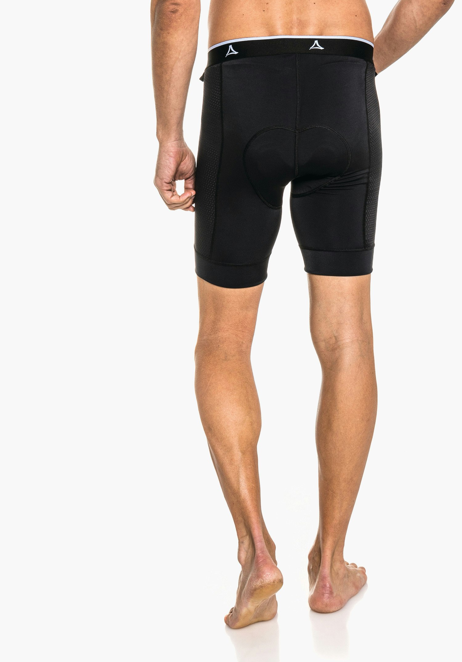 Skin Pants 4h M enge schwarze Radhose, von hinten getragen; Mann steht mit leichtem Schritt, nackte Beine sichtbar; weißer Hintergrund; Schöffel-Logo auf schwarzem Bund mit weißer Kante.