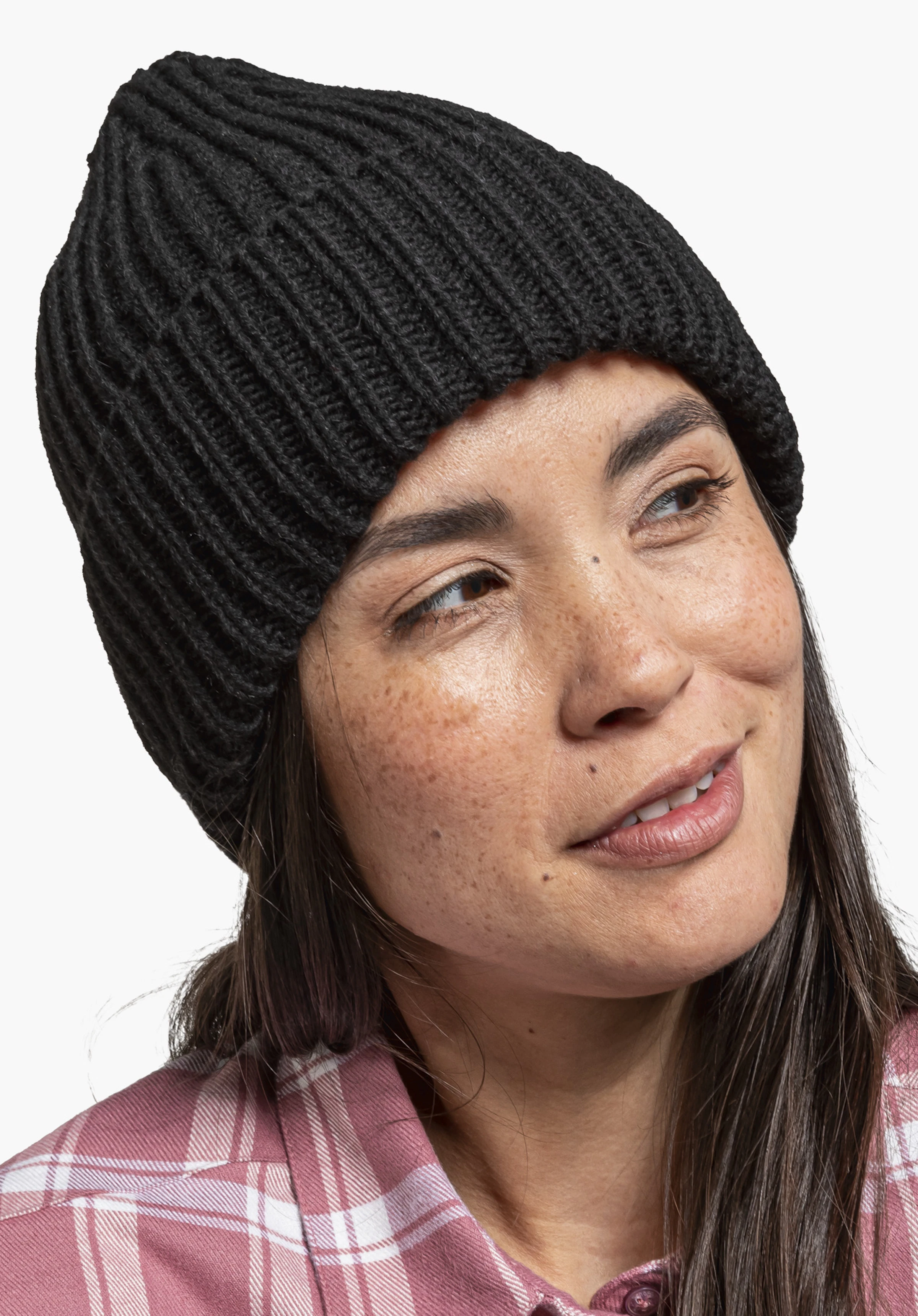 Knitted Hat Medford schwarze, gerippte Strickmütze sitzt auf dem Kopf einer lächelnden Frau; sie blickt nach rechts; weißer Hintergrund, rosa kariertes Hemd am Kragen sichtbar.