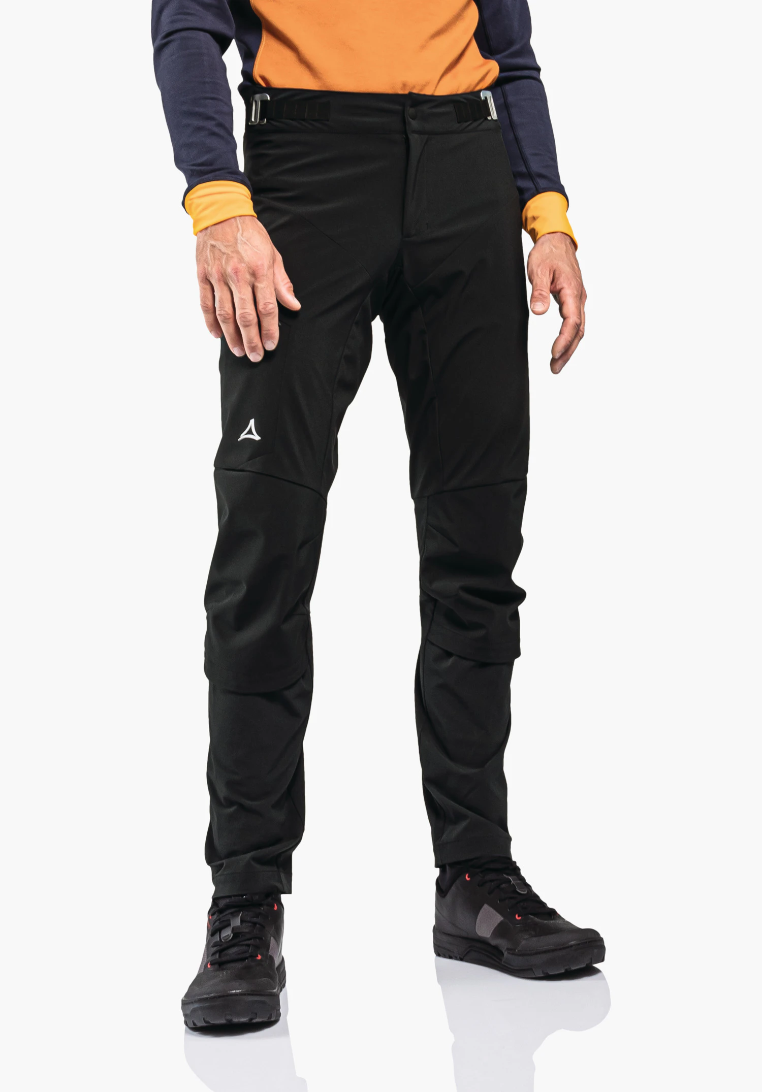 Hybrid Pants Tree Run M zwarte broek die de benen bedekt, met Schöffel-logo op de linker dij; persoon staat en draagt een donkerblauwe top met lichtoranje inzetstukken; lichtgrijze achtergrond.