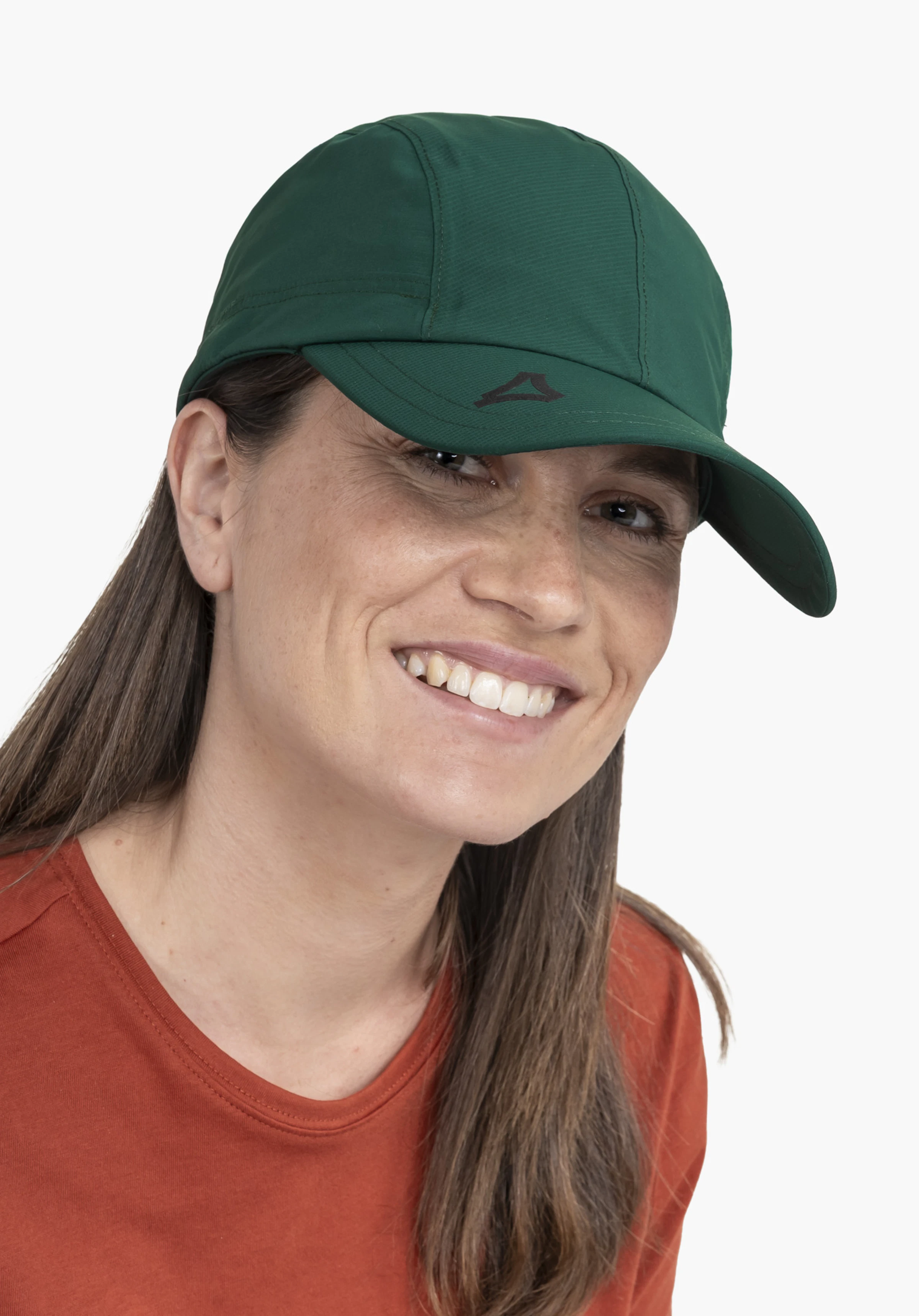 Rain Cap3 in diepgroen, gedragen door een glimlachende vrouw die lichtjes opzij in de camera kijkt. Het zwarte Schöffel-logo is subtiel op de klep geplaatst, tegen een neutrale achtergrond.