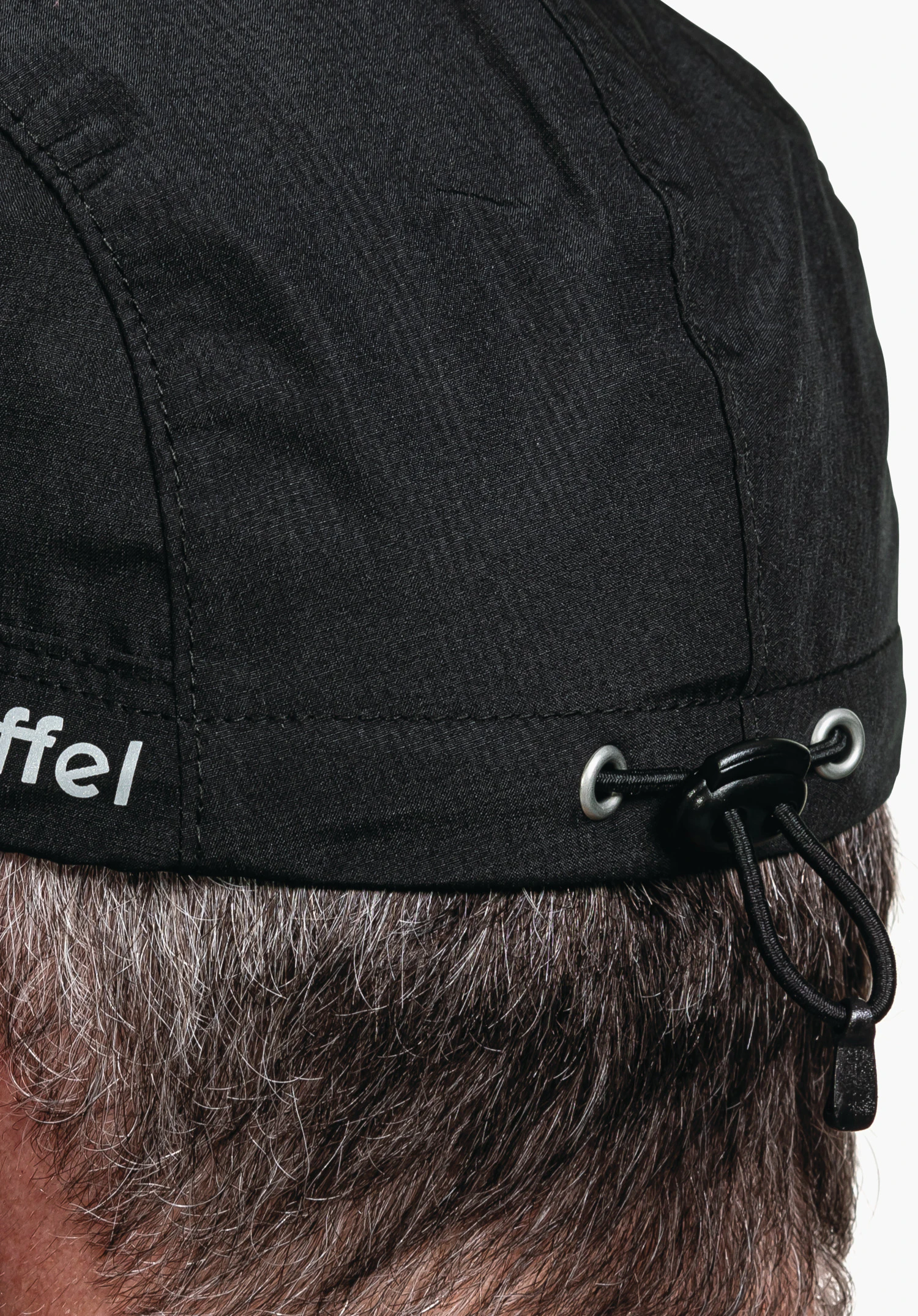 Rain Cap3 zeigt das schwarze, strukturierte Gewebe mit dem seitlichen Schöffel-Logo und dem verstellbaren Kordelzug-System am Hinterkopf. Nahaufnahme vor weißem Hintergrund.