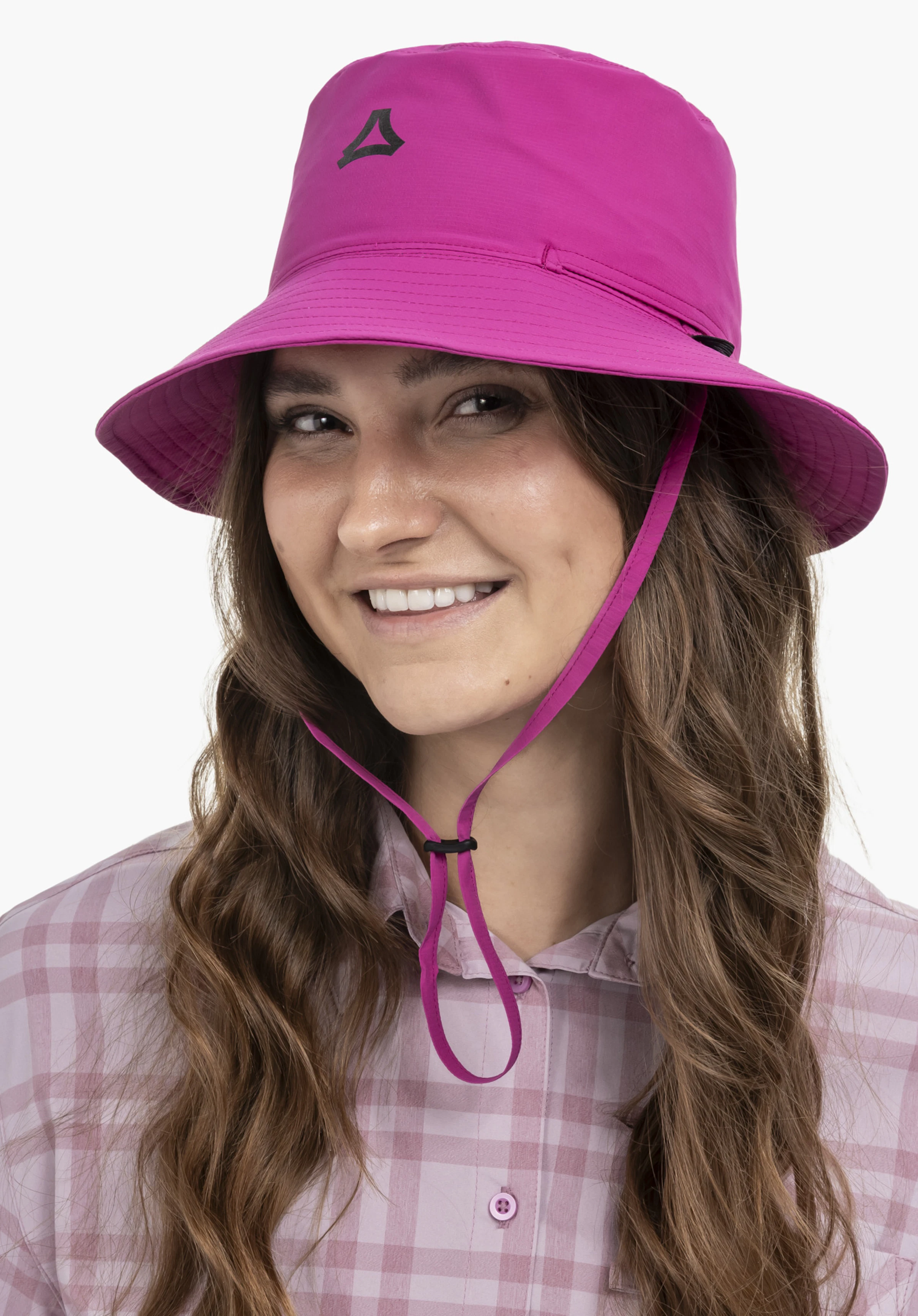 Rain Hat4 in Pink: Eine lächelnde Frau trägt den Hut auf dem Kopf, wobei das Schöffel-Logo auf der Vorderseite gut sichtbar ist. Die Aufnahme vor neutralem Hintergrund zeigt das Modell frontal, mit dem Kinnband des Hutes im Fokus.