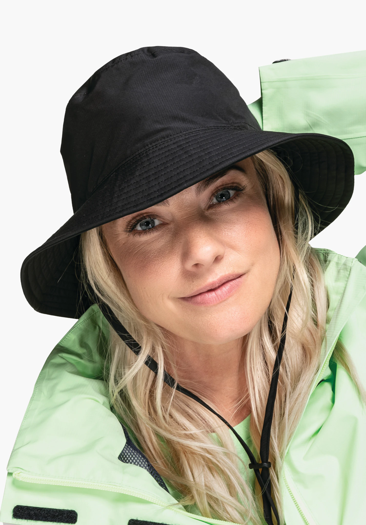 Rain Hat4 in Schwarz vor neutralem Hintergrund. Das Model ist frontal abgebildet und blickt direkt in die Kamera, während es den Hut mit Kinnband präsentiert.