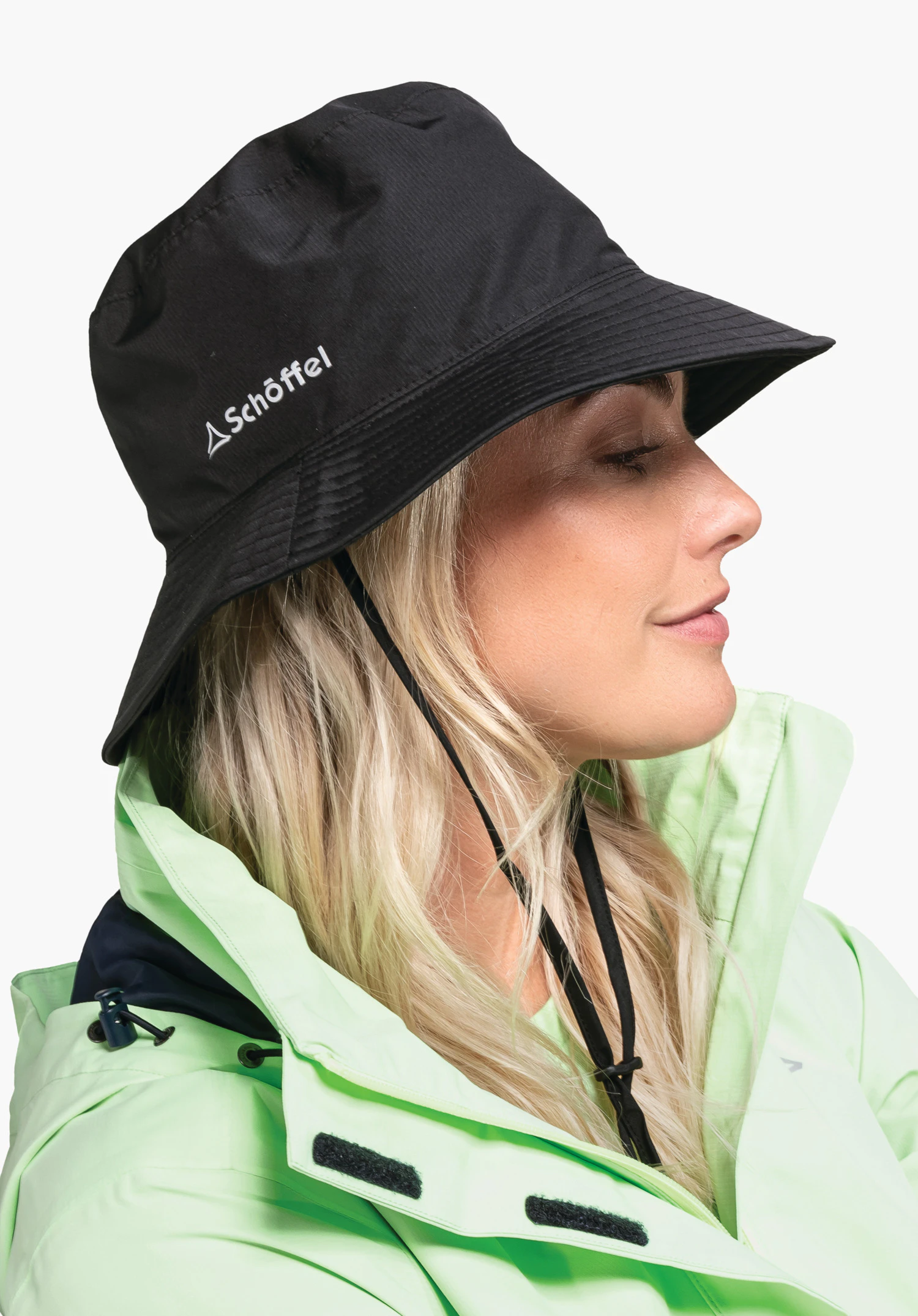 Rain Hat4 in Schwarz wird hier von einem Model im Profil getragen. Der Hut ist vor einem neutralen Hintergrund zu sehen, wobei das Schöffel-Logo seitlich gut erkennbar ist.