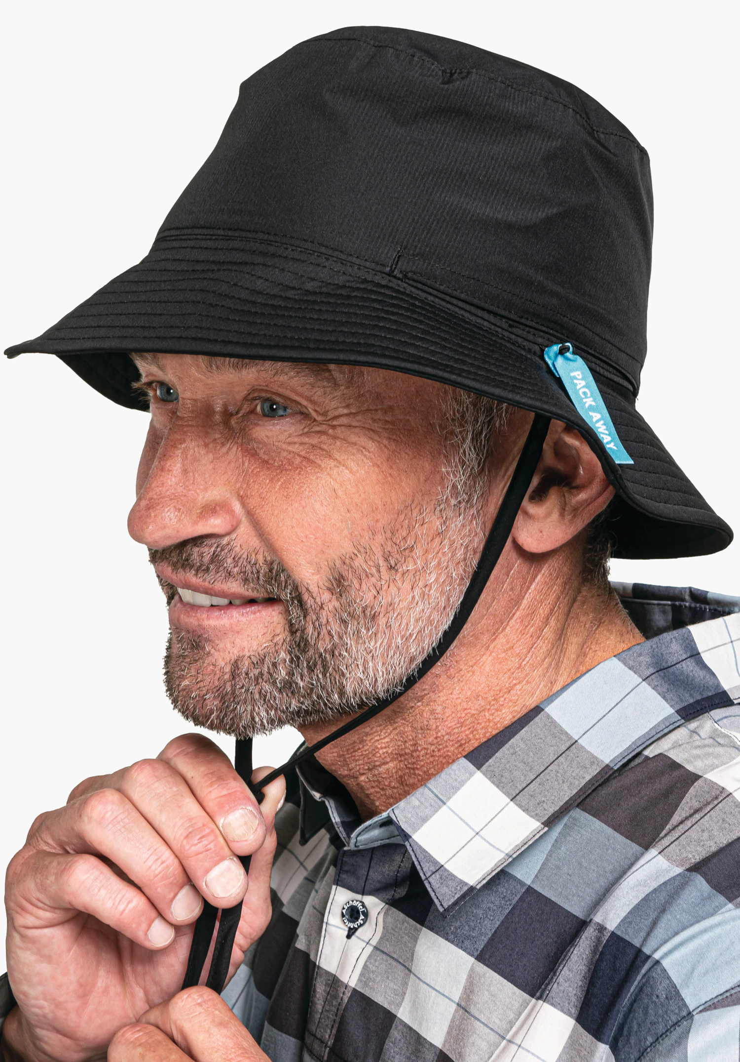 Rain Hat4 wird von einem Model in Nahaufnahme im Halbprofil getragen, das den Kinnriemen des schwarzen Hutes anpasst, abgelichtet vor einem neutralen Hintergrund.