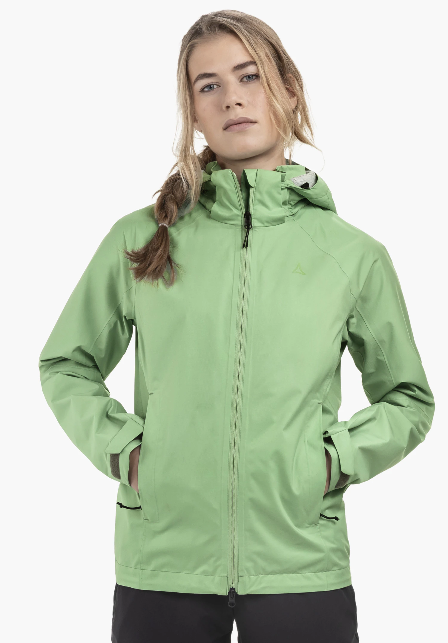 Jacket Easy XT L en vert, portée par un mannequin féminin qui se tient de face avec les mains dans les poches latérales. Le logo Schöffel est visible sur la poitrine gauche. Vue portée devant un fond neutre.