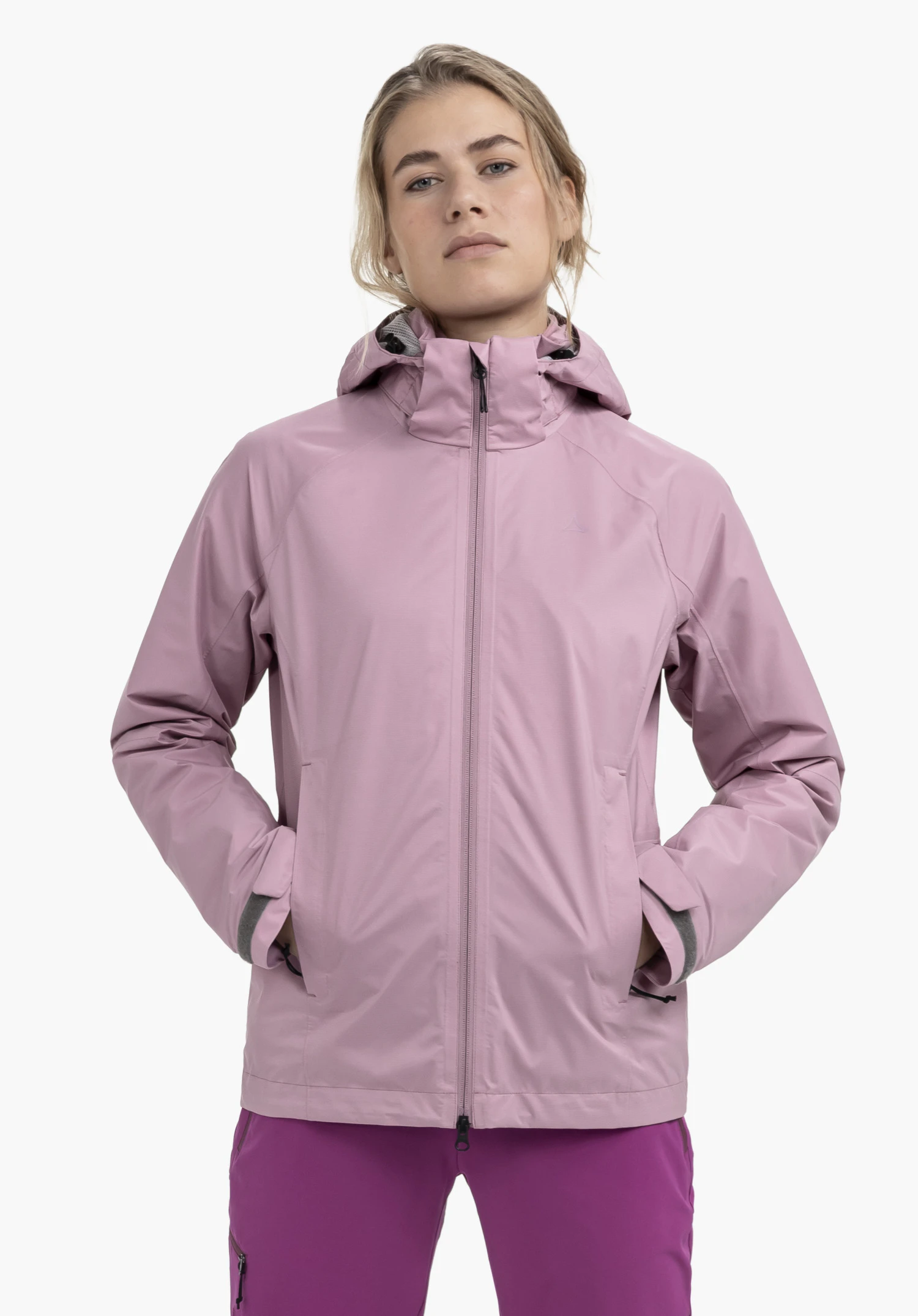 Jacket Easy XT L gedragen door een model dat frontaal staat met de handen in de zakken. De roze jas is gesloten en toont een subtiel Schöffel-logo op de linkerborst, gepresenteerd tegen een neutrale achtergrond.