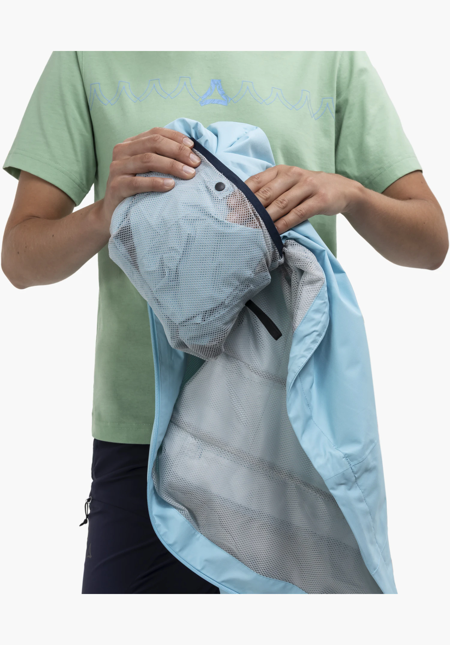 Jacket Easy XT L toont het opbergen van de blauwe stof in de geïntegreerde grijze gaaszak met donkerblauwe rand en zwarte drukknoop, close-up tegen een witte achtergrond.